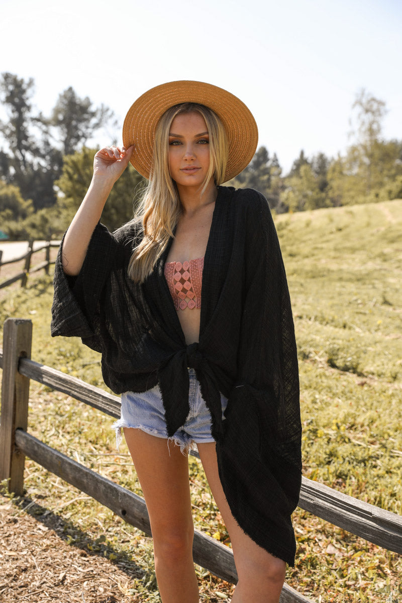 A stylish Flounce Tie-Front Kimono Wrap featuring a lightweight fabric, feminine tie-front closure, and comfortable kimono sleeves, perfect for layering.