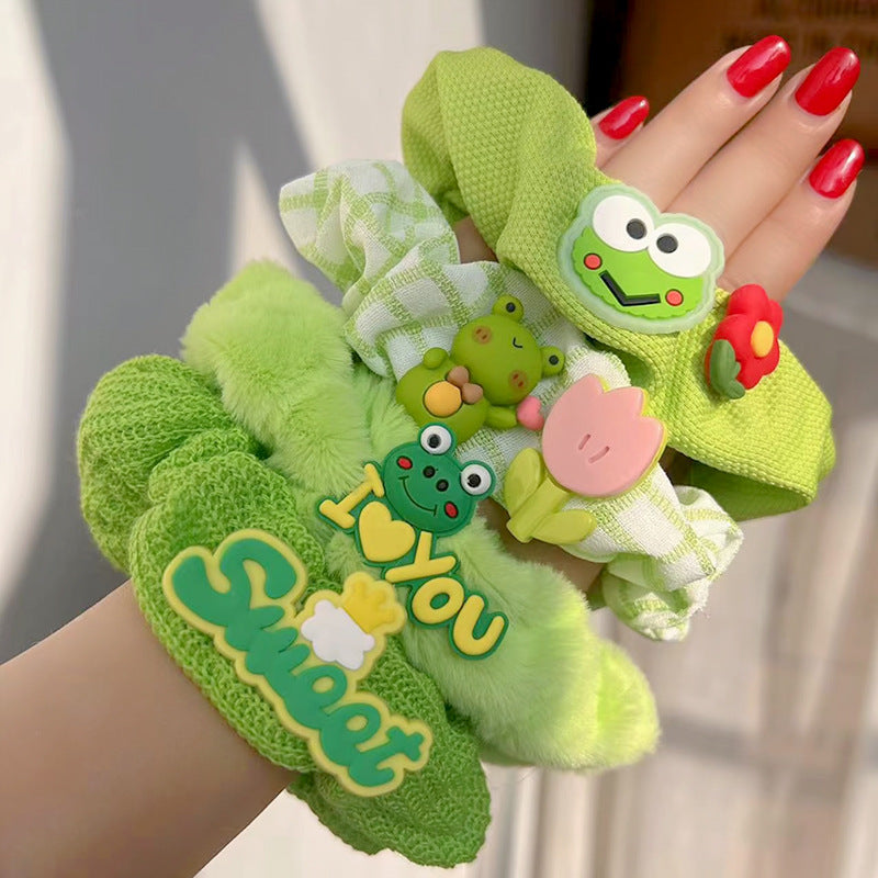 A charming green frog hair tie featuring a whimsical design, perfect for adding playful elegance to hairstyles.