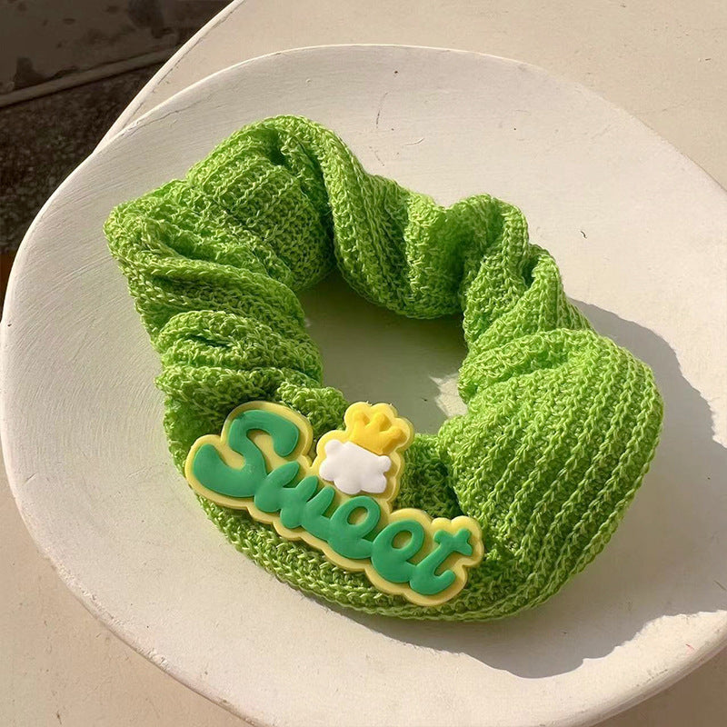 A charming green frog hair tie featuring a whimsical design, perfect for adding playful elegance to hairstyles.