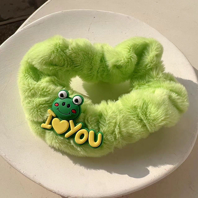 A charming green frog hair tie featuring a whimsical design, perfect for adding playful elegance to hairstyles.