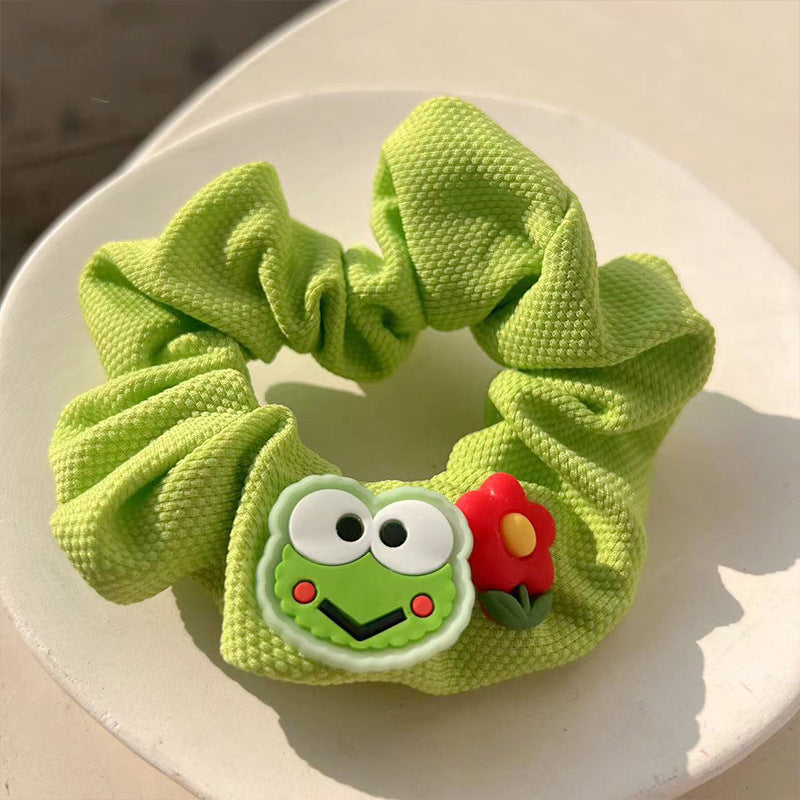 A charming green frog hair tie featuring a whimsical design, perfect for adding playful elegance to hairstyles.