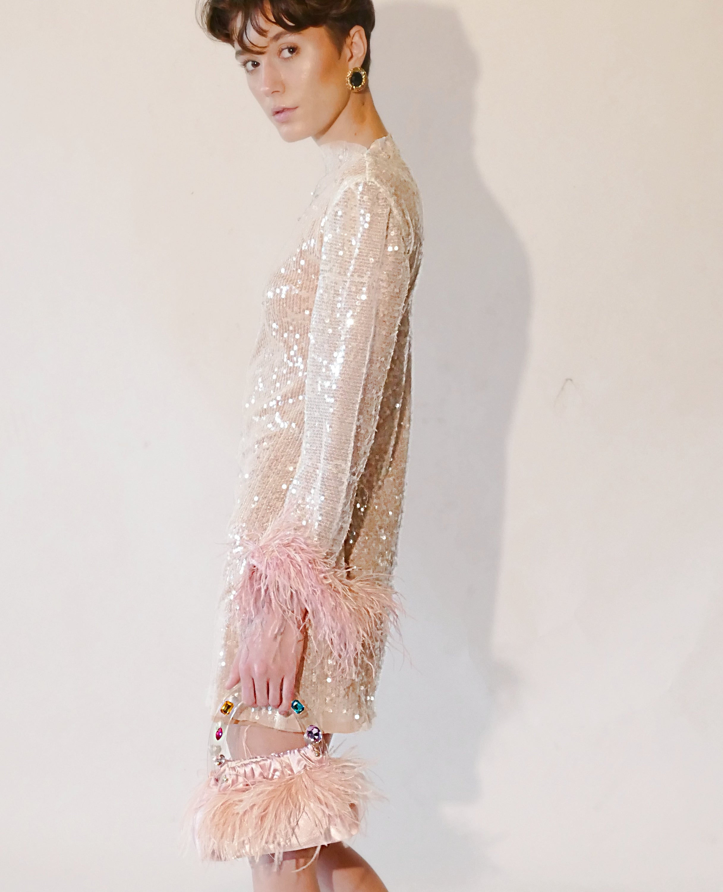 A stunning handmade party dress featuring sequins and feather trim, with long bell sleeves and a chic vegan leather design.