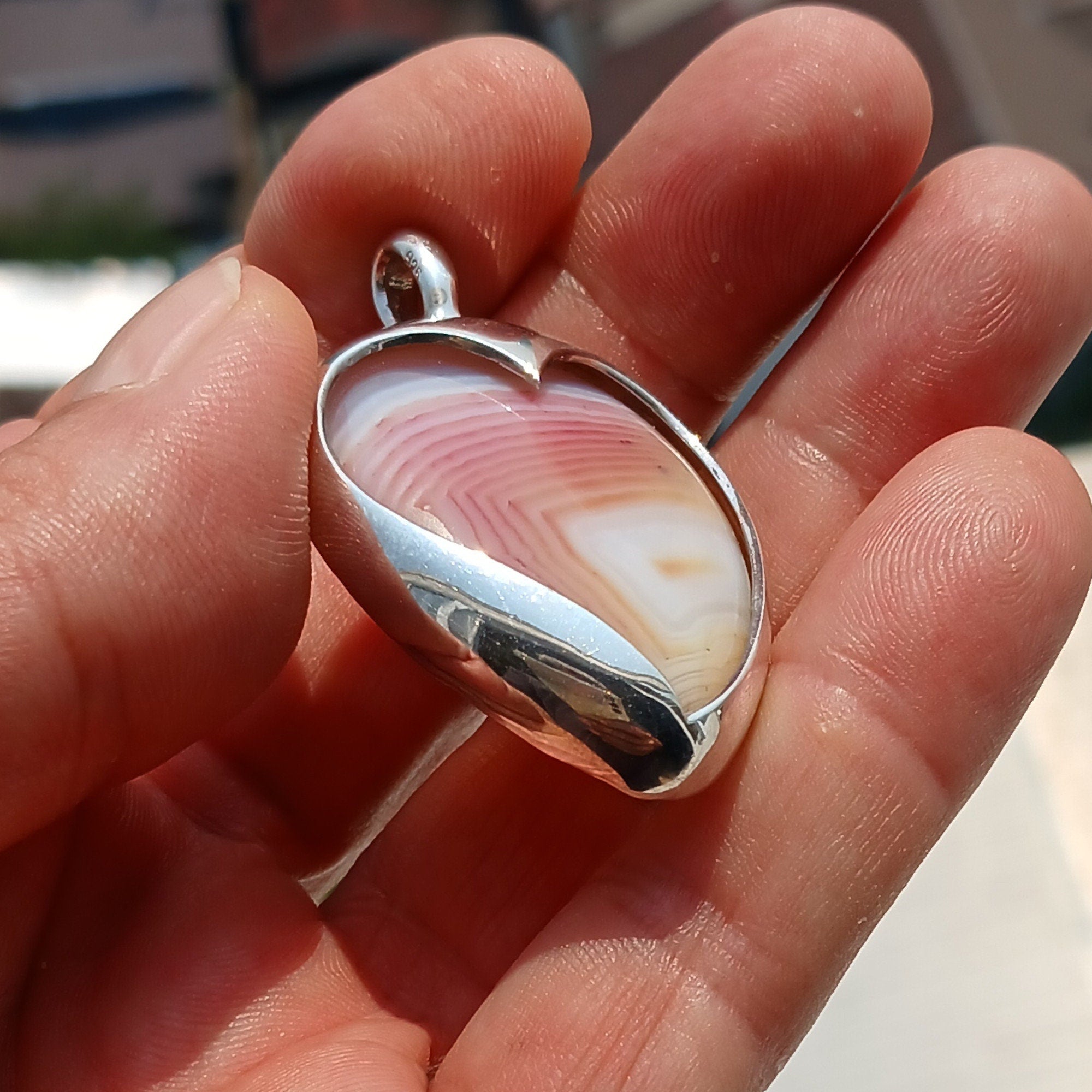 Sterling silver heart pendant featuring a pink and white agate cabochon, elegantly designed for a unique jewelry piece.