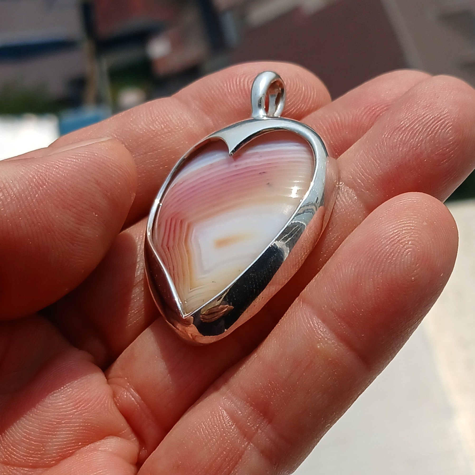 Sterling silver heart pendant featuring a pink and white agate cabochon, elegantly designed for a unique jewelry piece.