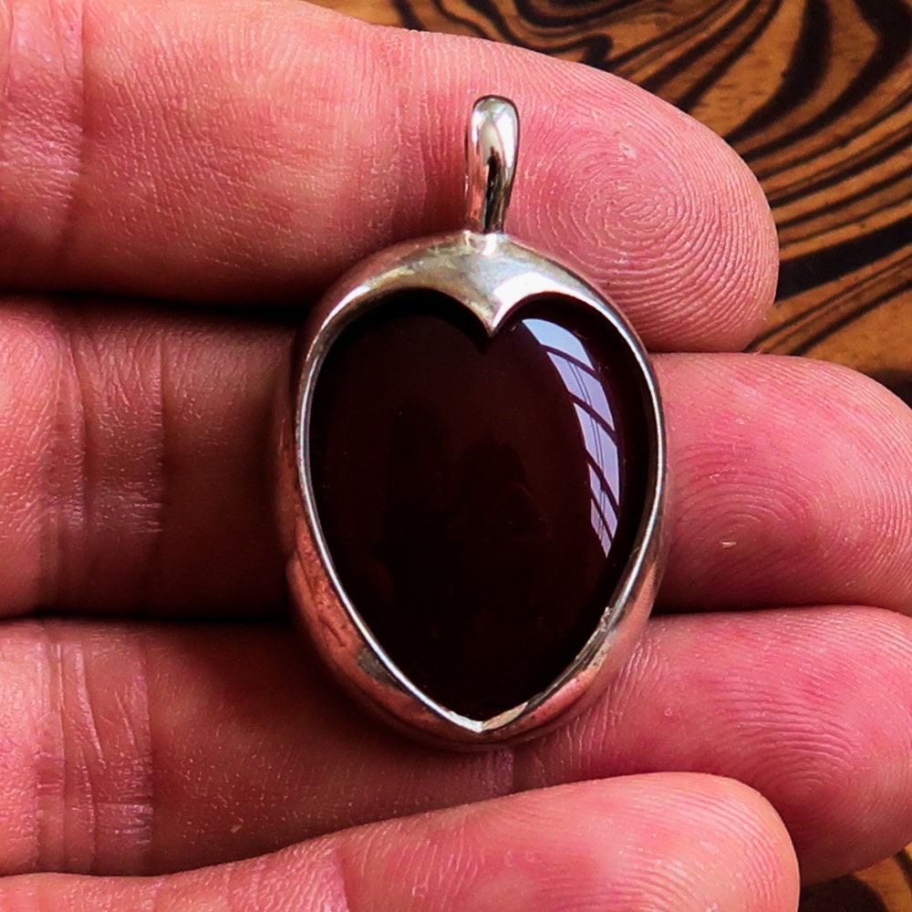 A stunning heart pendant made of sterling silver featuring a vibrant orange Agate Cabochon, showcasing its unique design and quality craftsmanship.