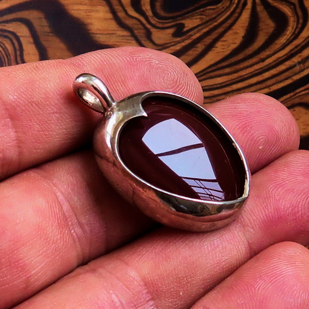 A stunning heart pendant made of sterling silver featuring a vibrant orange Agate Cabochon, showcasing its unique design and quality craftsmanship.