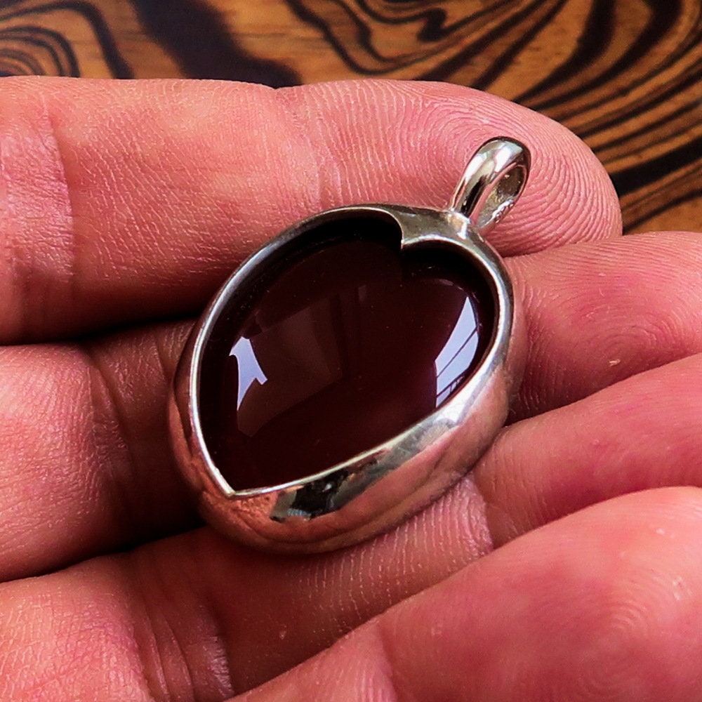 A stunning heart pendant made of sterling silver featuring a vibrant orange Agate Cabochon, showcasing its unique design and quality craftsmanship.