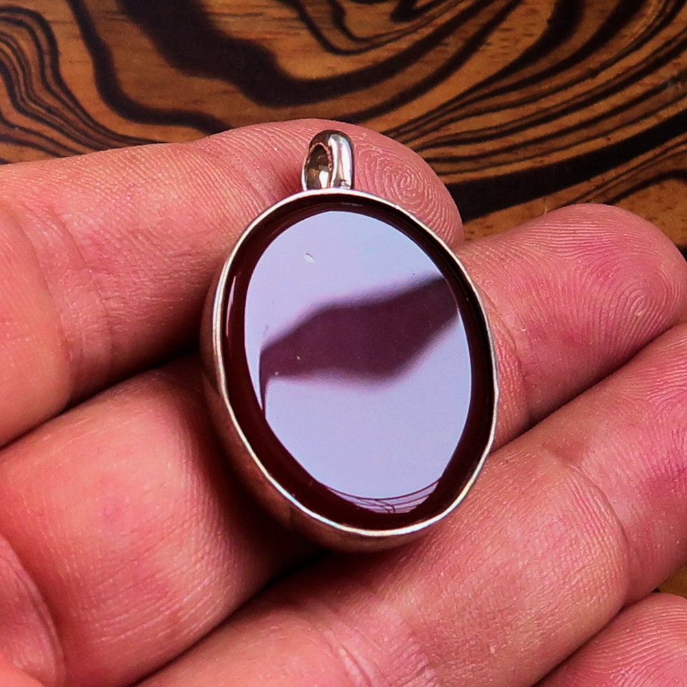 A stunning heart pendant made of sterling silver featuring a vibrant orange Agate Cabochon, showcasing its unique design and quality craftsmanship.