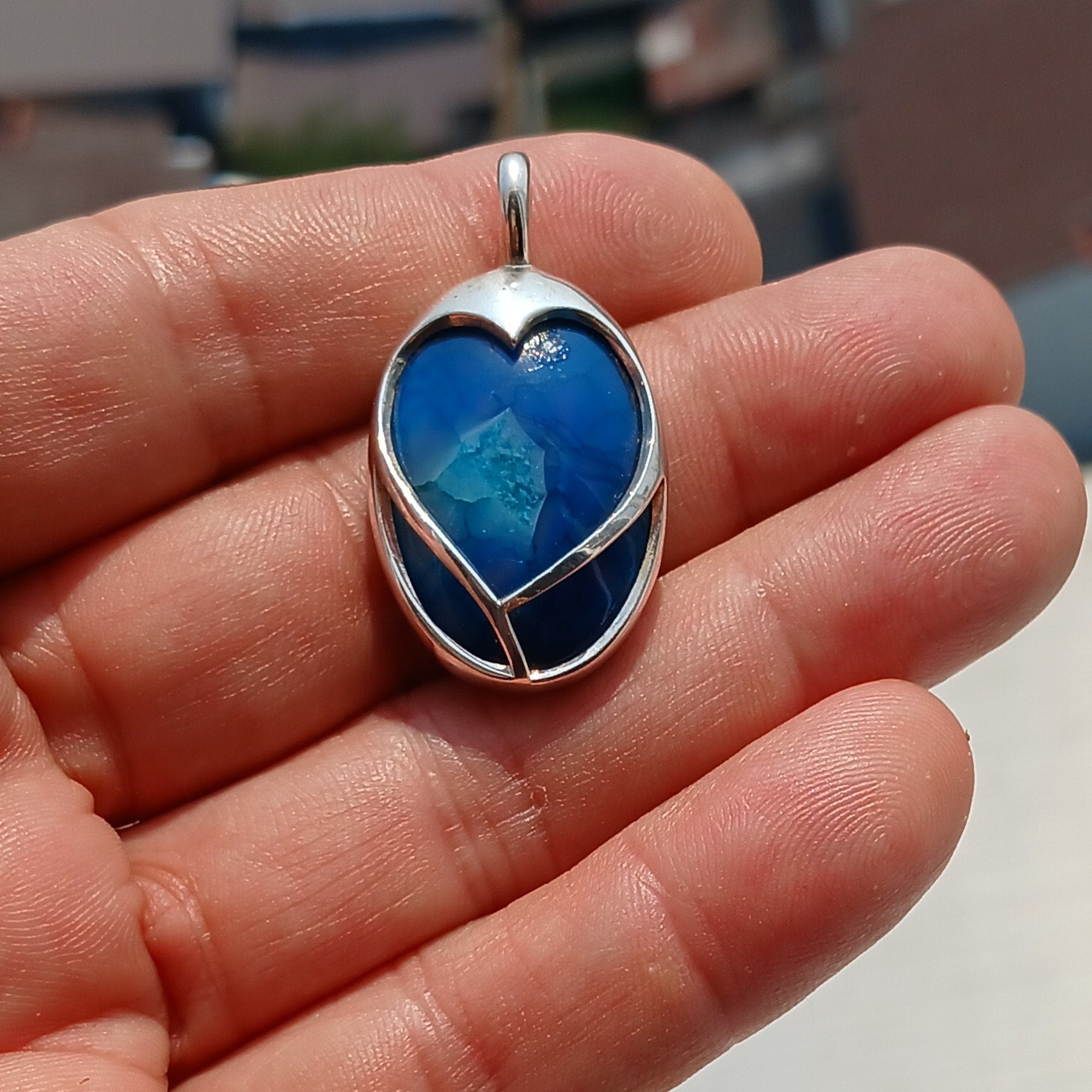 A beautiful heart-shaped sterling silver pendant featuring a blue agate cabochon, showcasing intricate craftsmanship and elegant design.