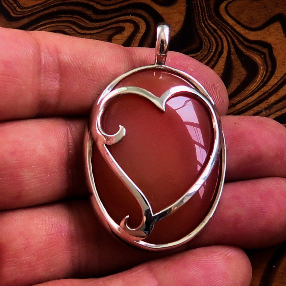 Heart Silver Pendant made of sterling silver featuring a vibrant orange Agate cabochon at the center, showcasing intricate details.