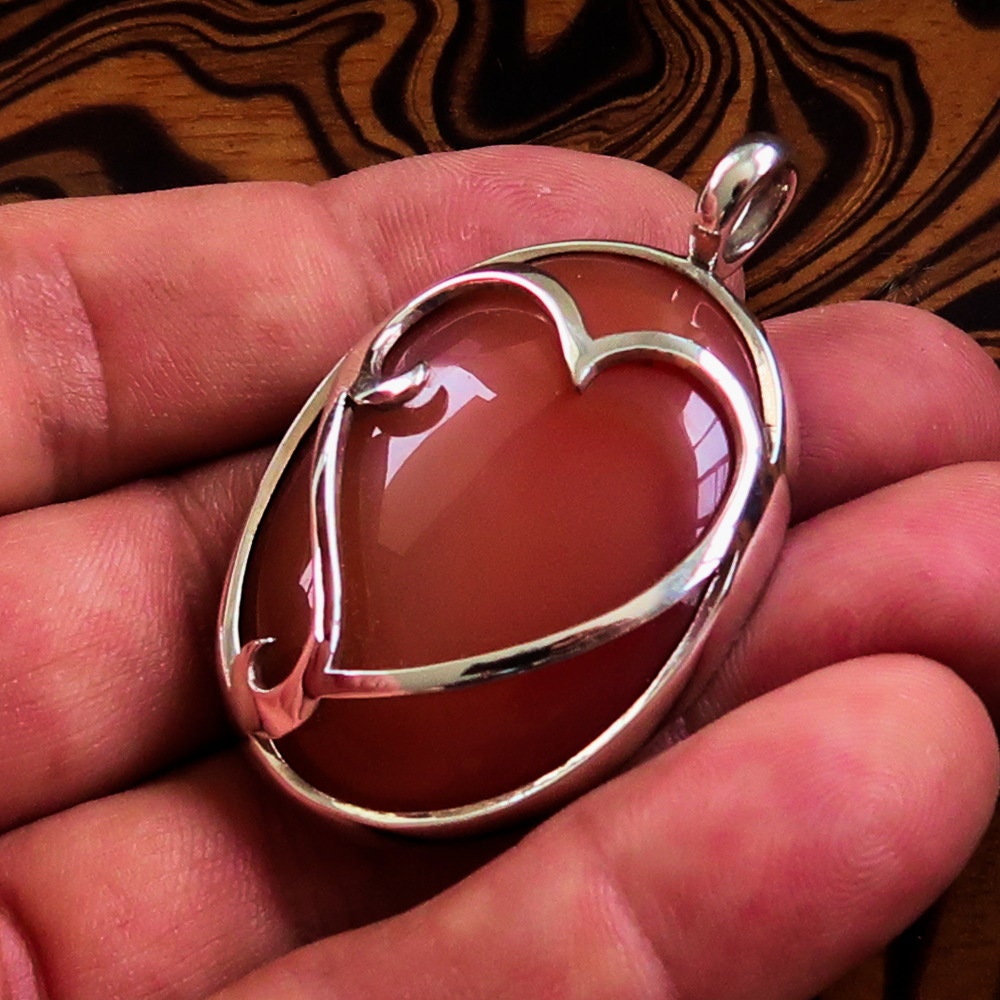 Heart Silver Pendant made of sterling silver featuring a vibrant orange Agate cabochon at the center, showcasing intricate details.