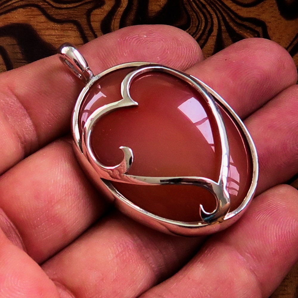 Heart Silver Pendant made of sterling silver featuring a vibrant orange Agate cabochon at the center, showcasing intricate details.