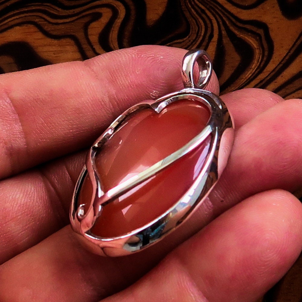 Heart Silver Pendant made of sterling silver featuring a vibrant orange Agate cabochon at the center, showcasing intricate details.