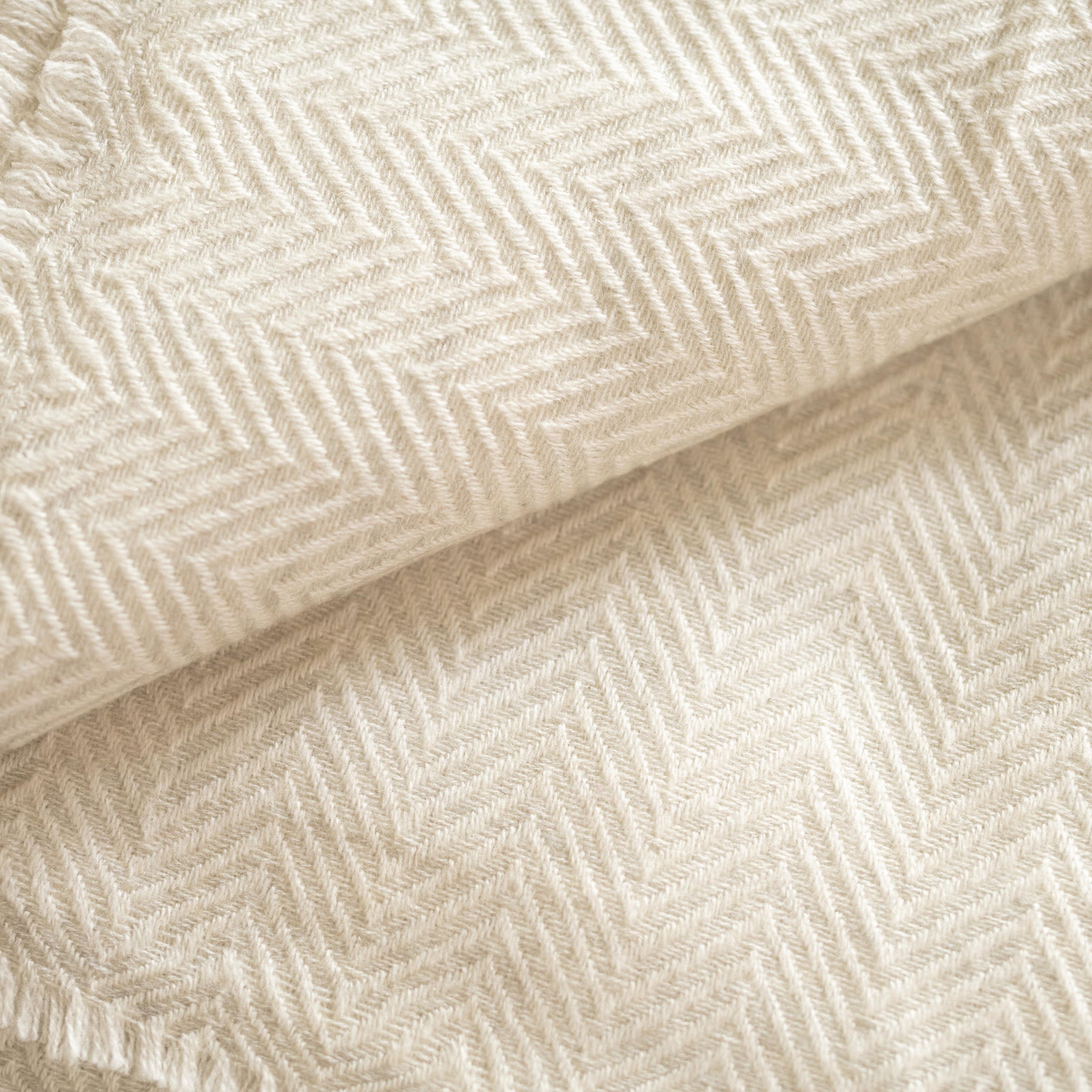 Luxuriöse weiße Kaschmirdecke mit großem Fischgrätenmuster, handgewebt in Nepal, ideal für stilvolle Wohnräume.