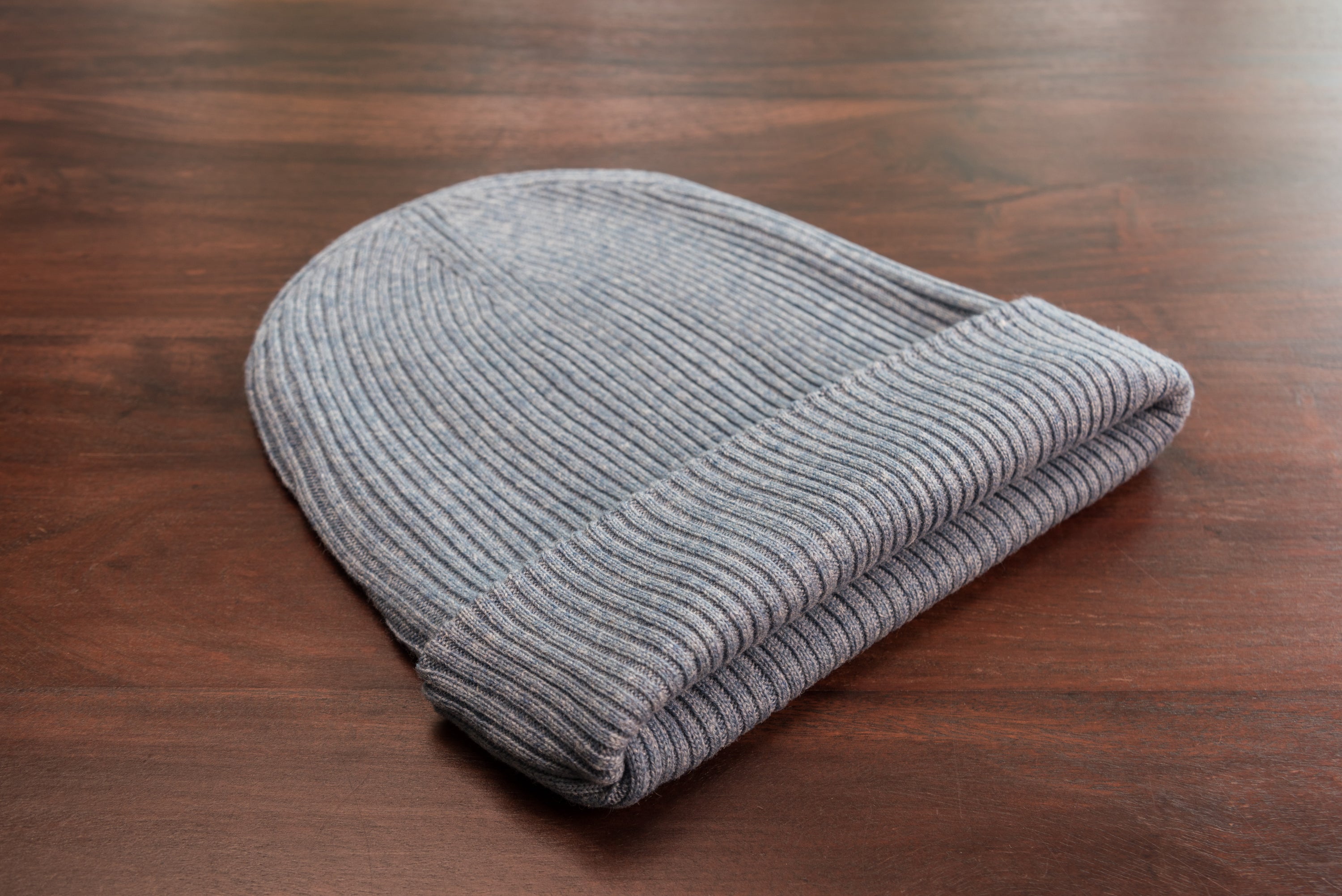 A stylish blue ribbed cashmere beanie with a fold, showcasing its luxurious texture and craftsmanship.
