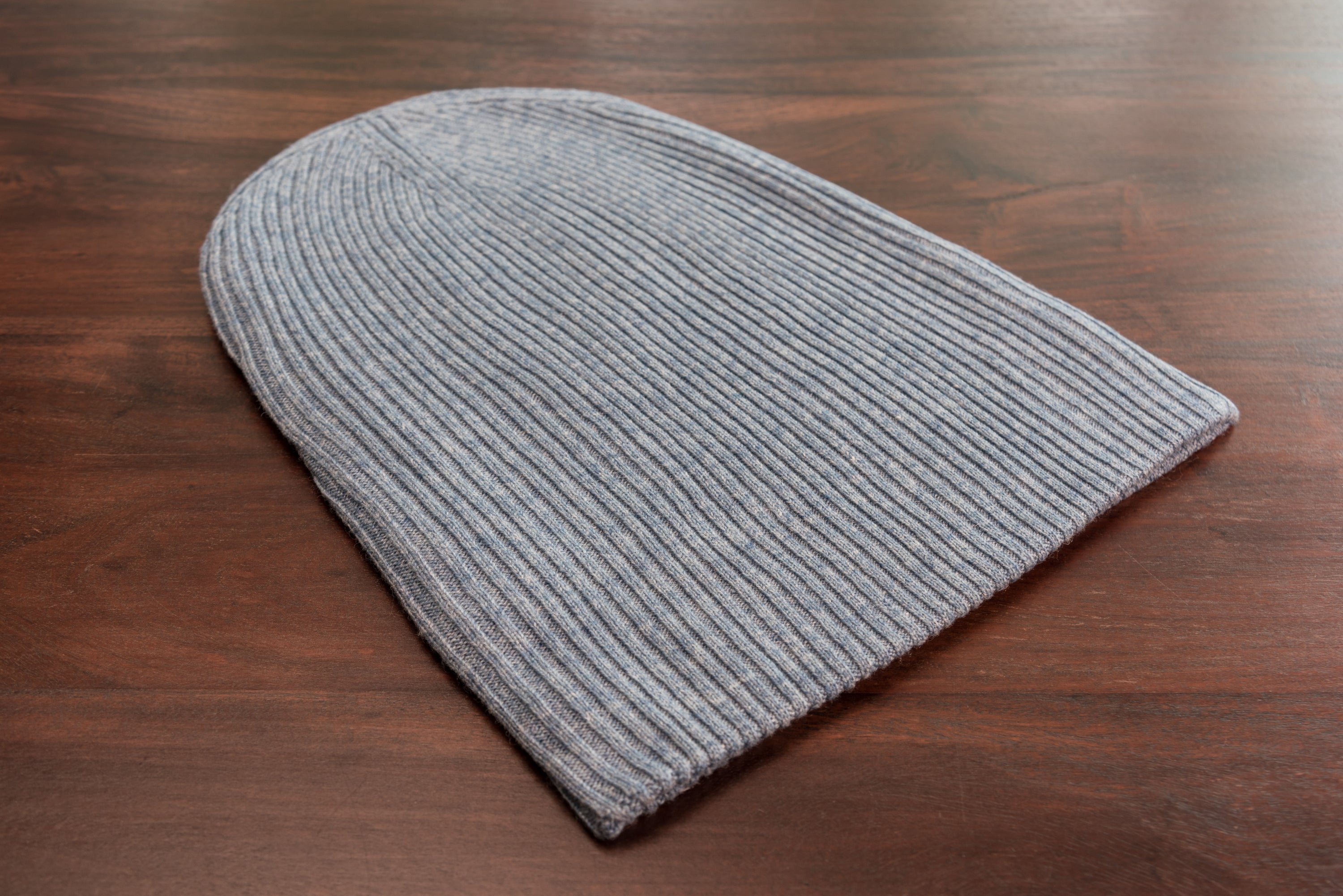 A stylish blue ribbed cashmere beanie with a fold, showcasing its luxurious texture and craftsmanship.
