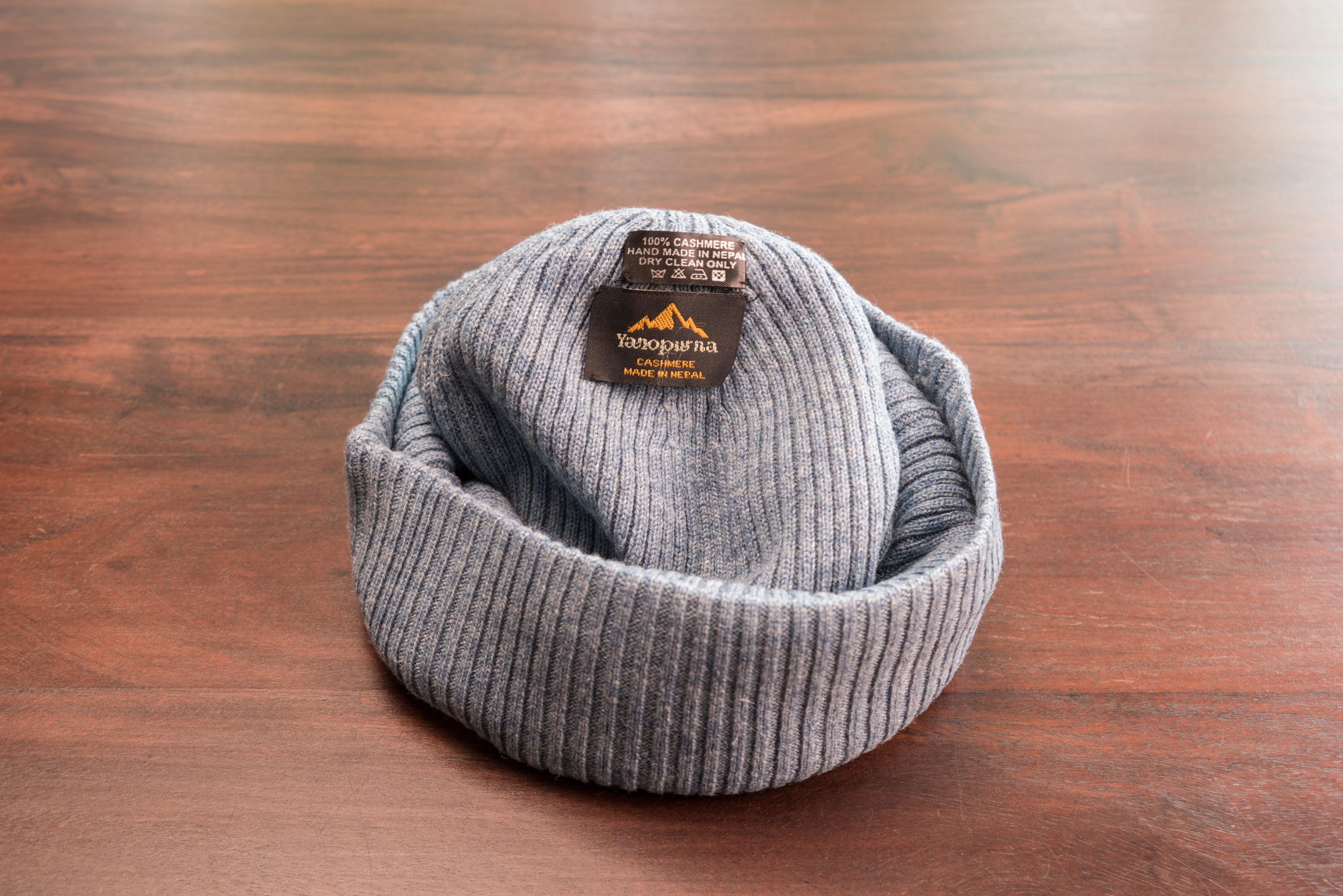 A stylish blue ribbed cashmere beanie with a fold, showcasing its luxurious texture and craftsmanship.