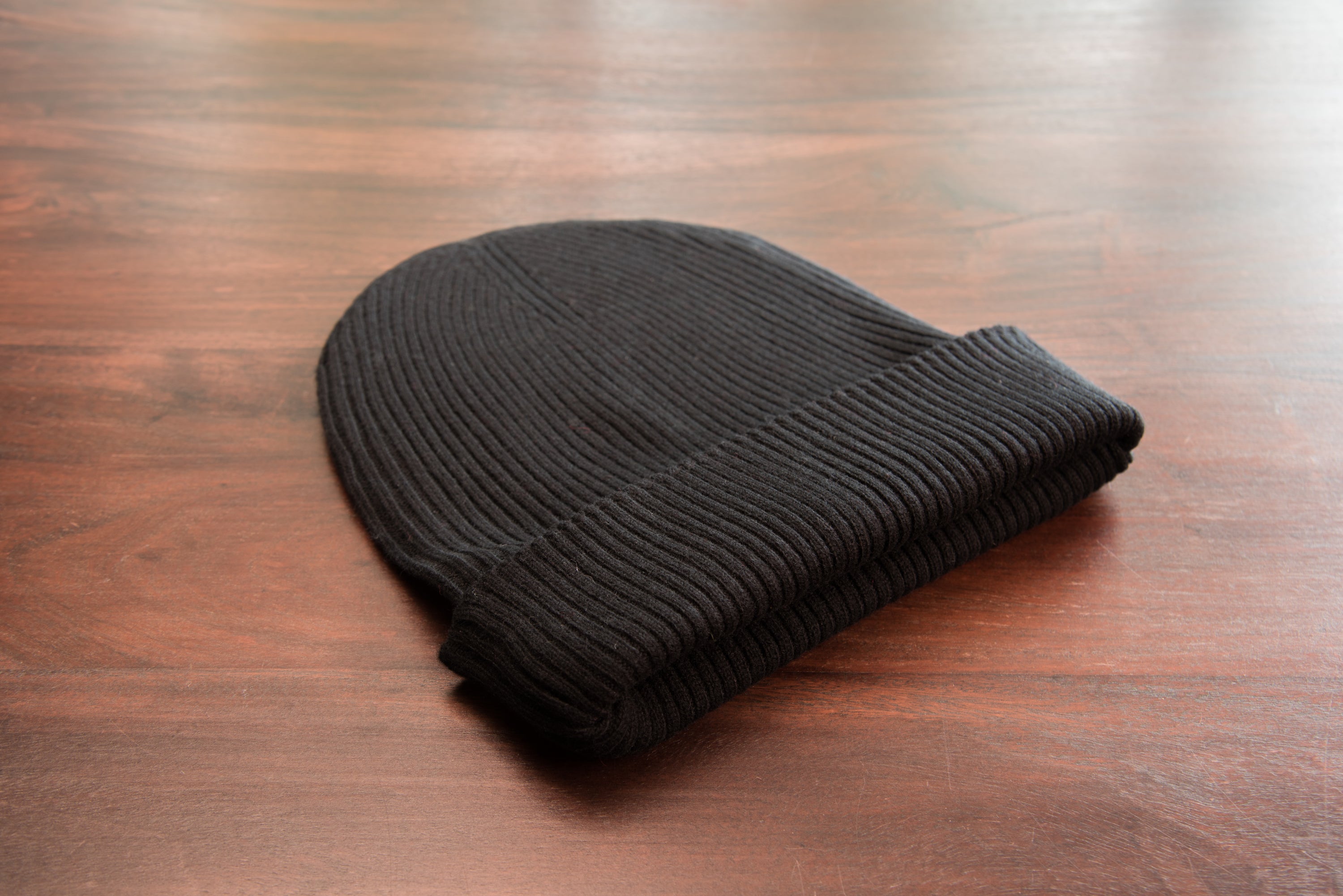 A stylish black ribbed cashmere beanie with a fold, showcasing its luxurious texture and craftsmanship.
