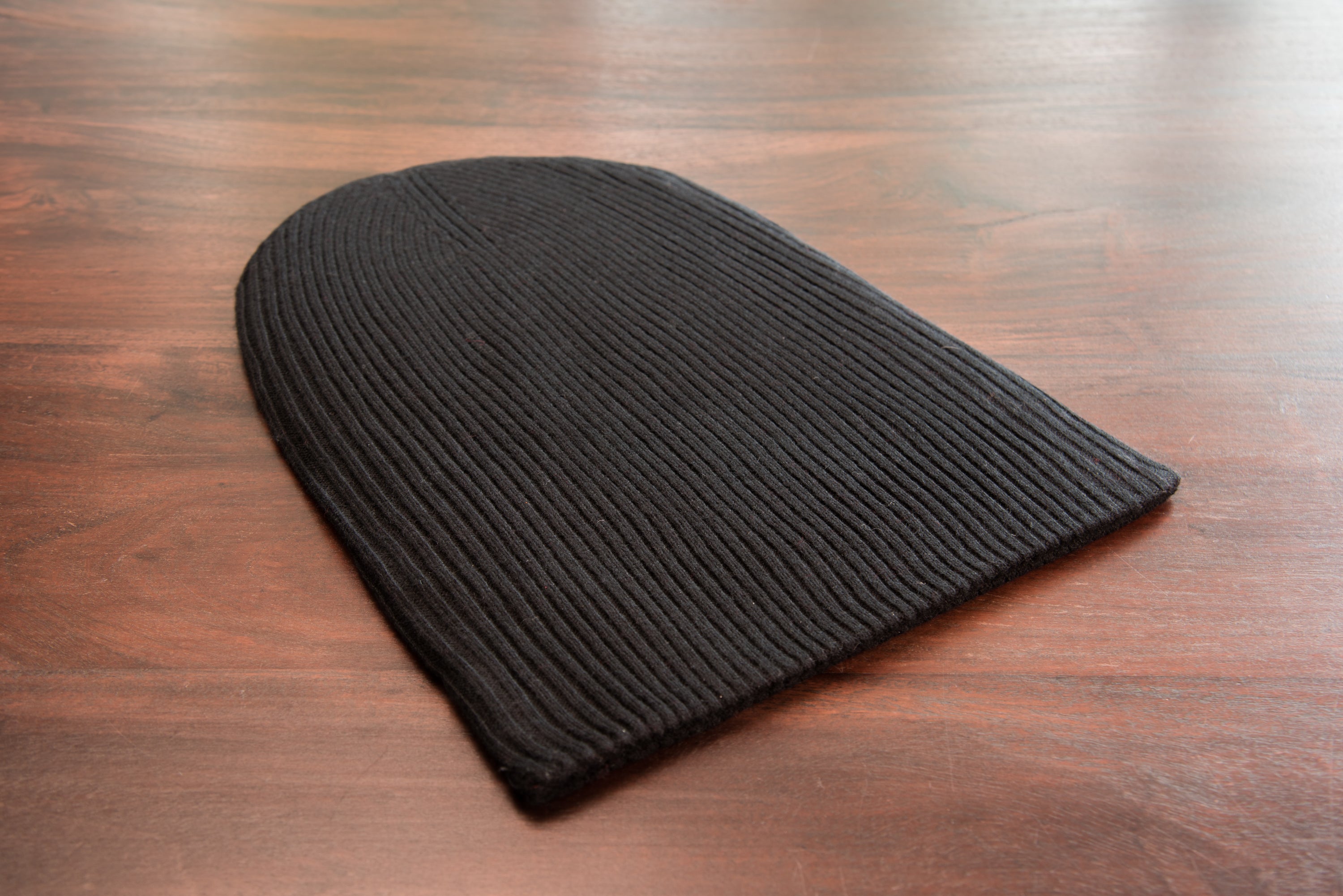 A stylish black ribbed cashmere beanie with a fold, showcasing its luxurious texture and craftsmanship.