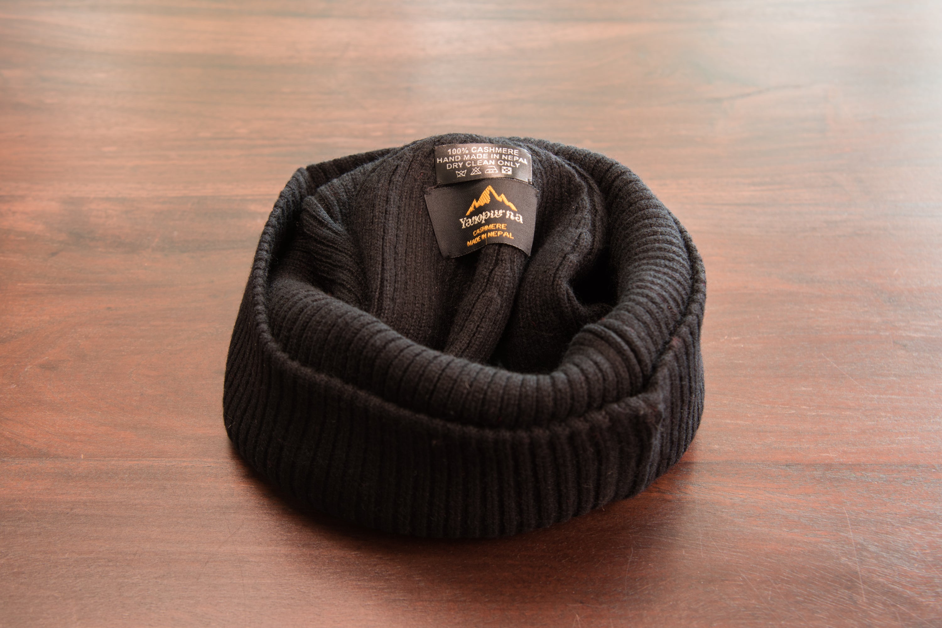 A stylish black ribbed cashmere beanie with a fold, showcasing its luxurious texture and craftsmanship.
