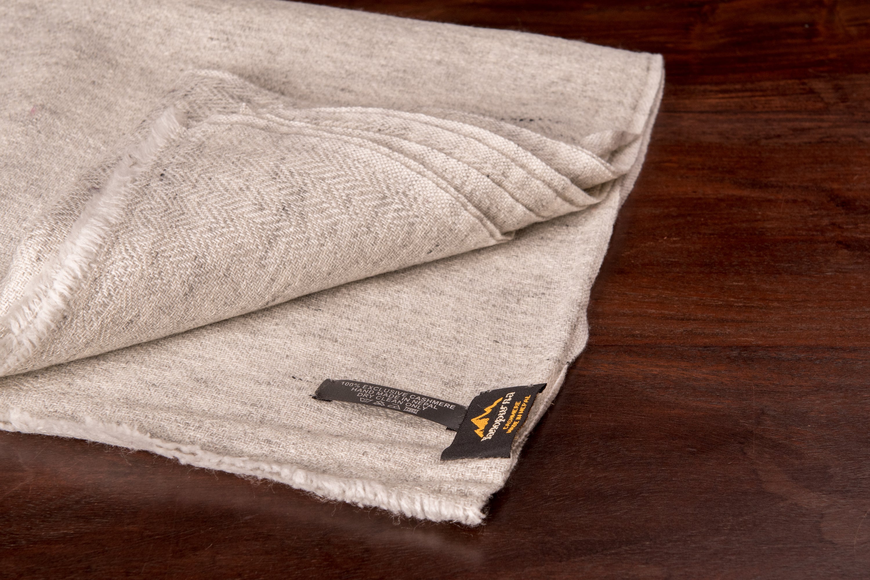 Hellgraues Kaschmirtuch mit Fischgrätenmuster, handgewebt in Nepal, leicht und elegant.