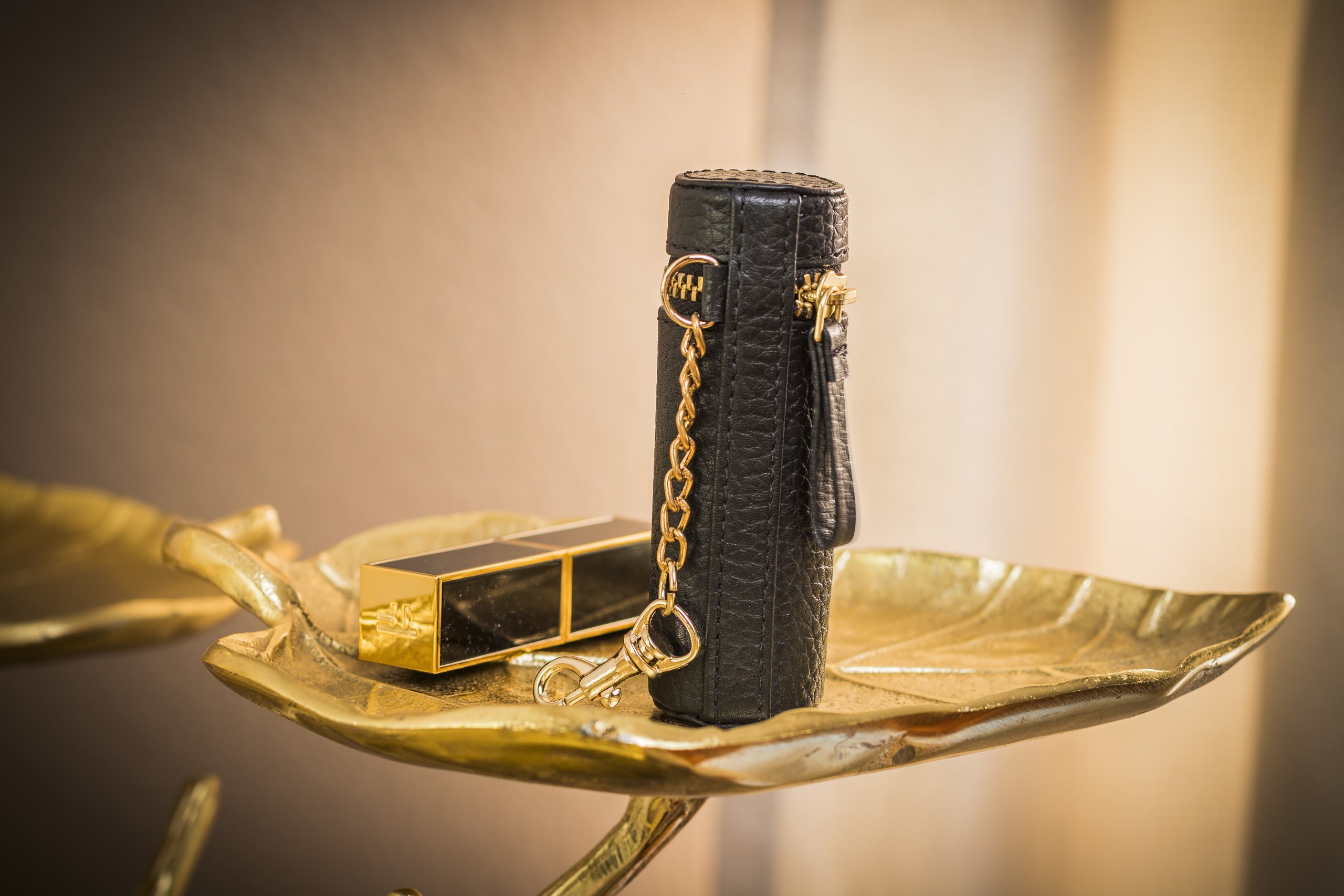 A stylish Lipstick Keeper made of genuine pebble leather, designed to hold lipsticks and chapsticks, featuring a compact size and attachment for bags.