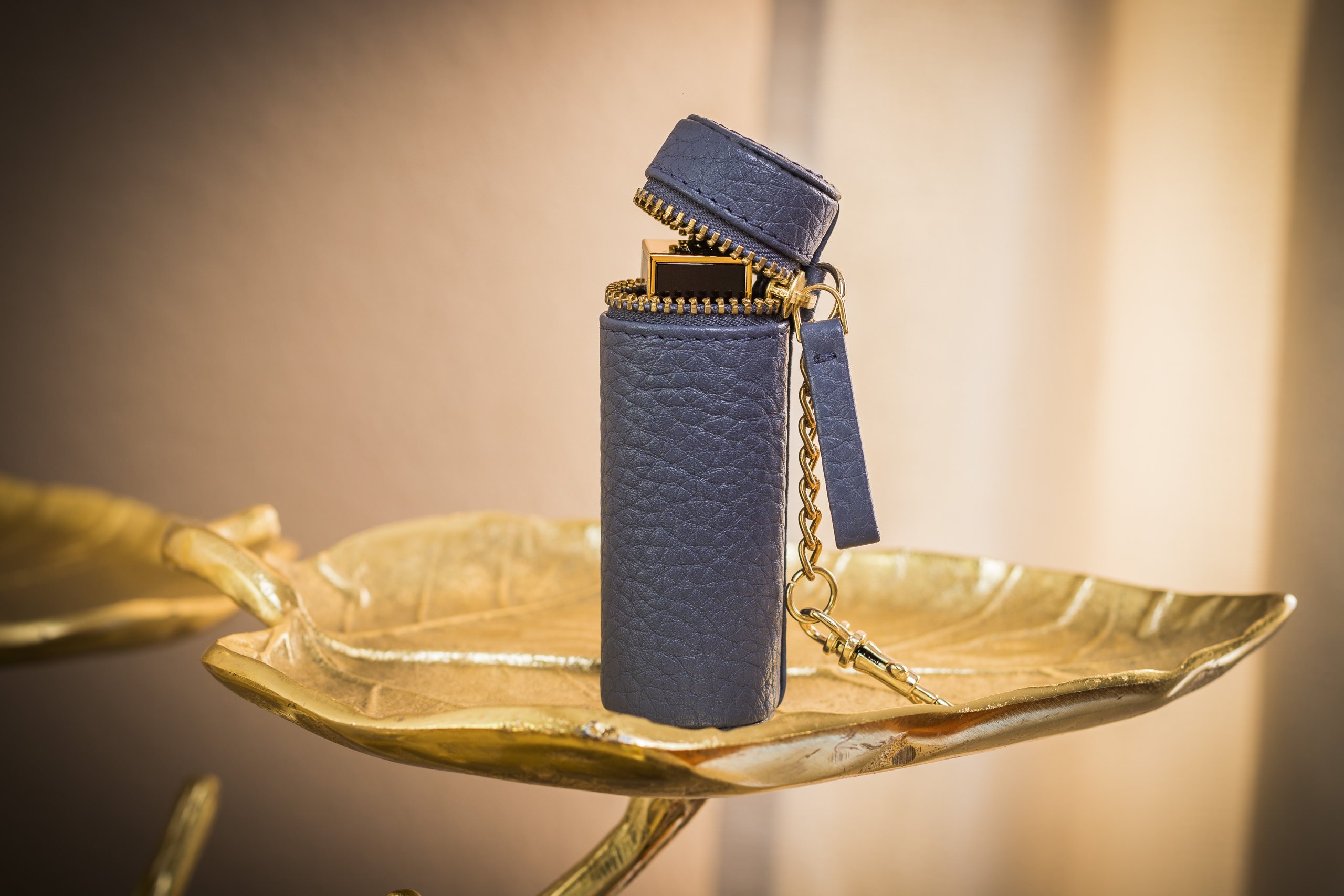 A stylish Lipstick Keeper made of genuine pebble leather, designed to hold lipsticks and chapsticks, featuring a compact size and attachment for bags.