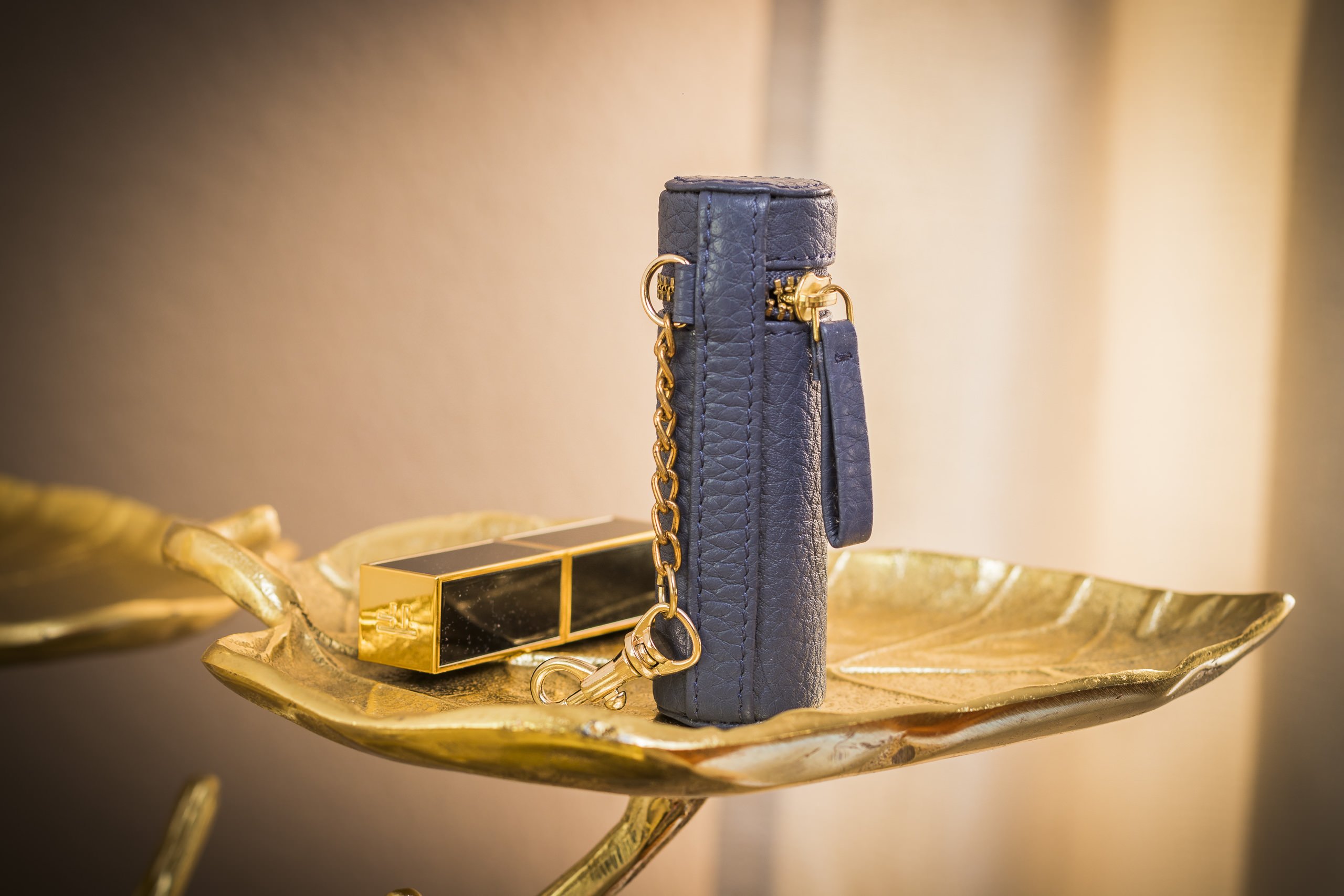 A stylish Lipstick Keeper made of genuine pebble leather, designed to hold lipsticks and chapsticks, featuring a compact size and attachment for bags.