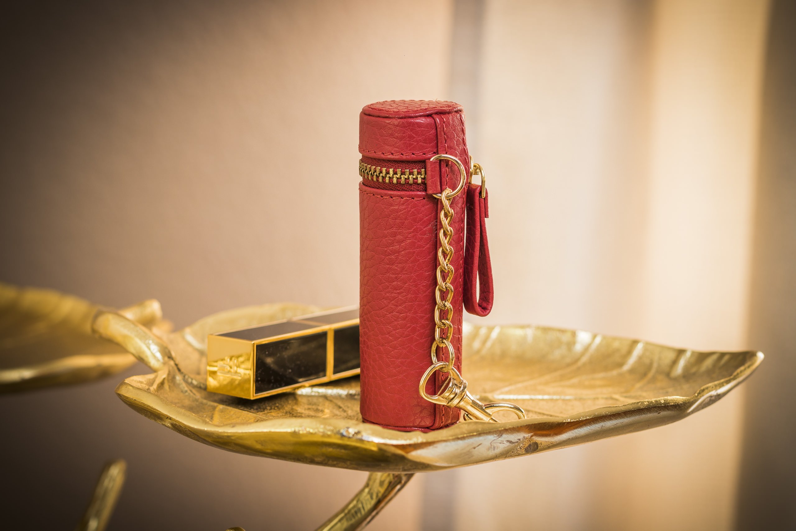 A stylish Lipstick Keeper made of genuine pebble leather, designed to hold lipsticks and chapsticks, featuring a compact size and attachment for bags.