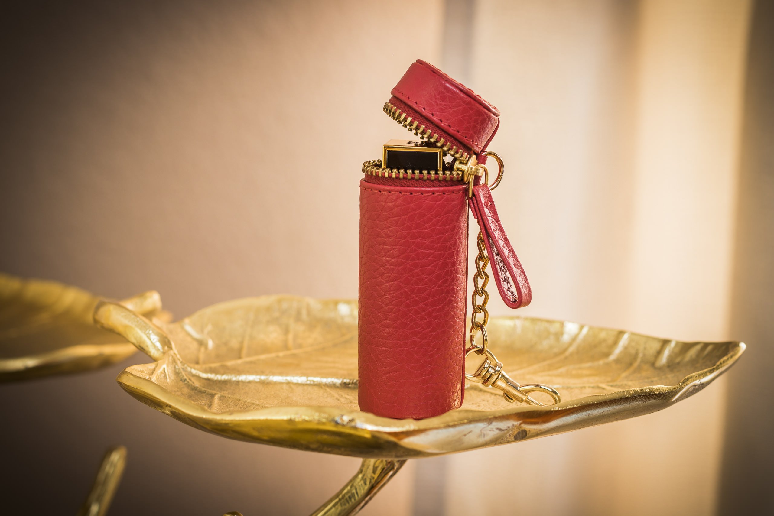 A stylish Lipstick Keeper made of genuine pebble leather, designed to hold lipsticks and chapsticks, featuring a compact size and attachment for bags.