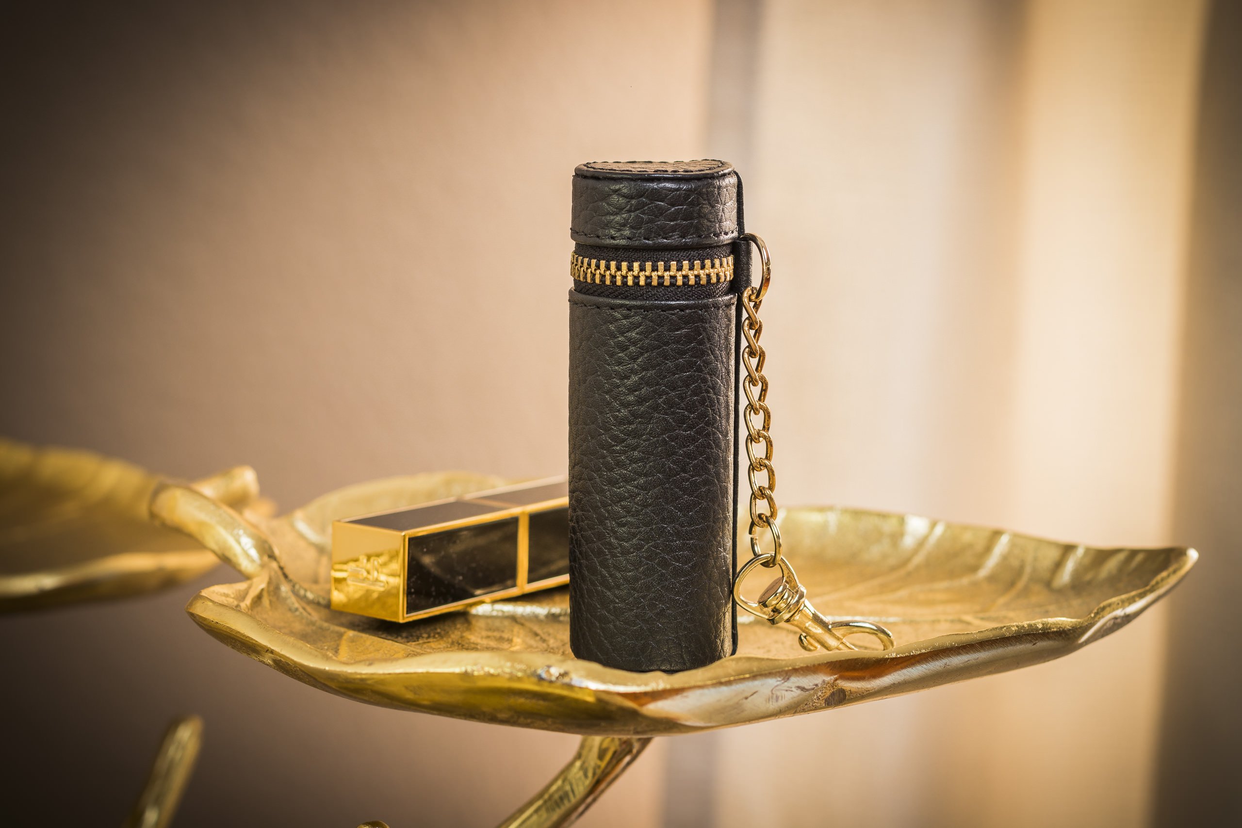 A stylish Lipstick Keeper made of genuine pebble leather, designed to hold lipsticks and chapsticks, featuring a compact size and attachment for bags.