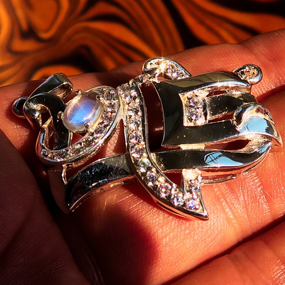 Sterling silver Love Pendant featuring a moonstone centerpiece and cubic zirconia accents, elegantly designed with the word 'LOVE'.