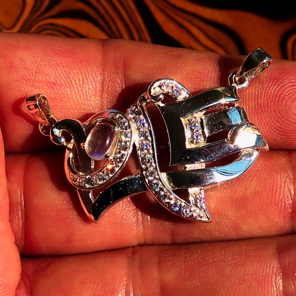 Sterling silver Love Pendant featuring a moonstone centerpiece and cubic zirconia accents, elegantly designed with the word 'LOVE'.