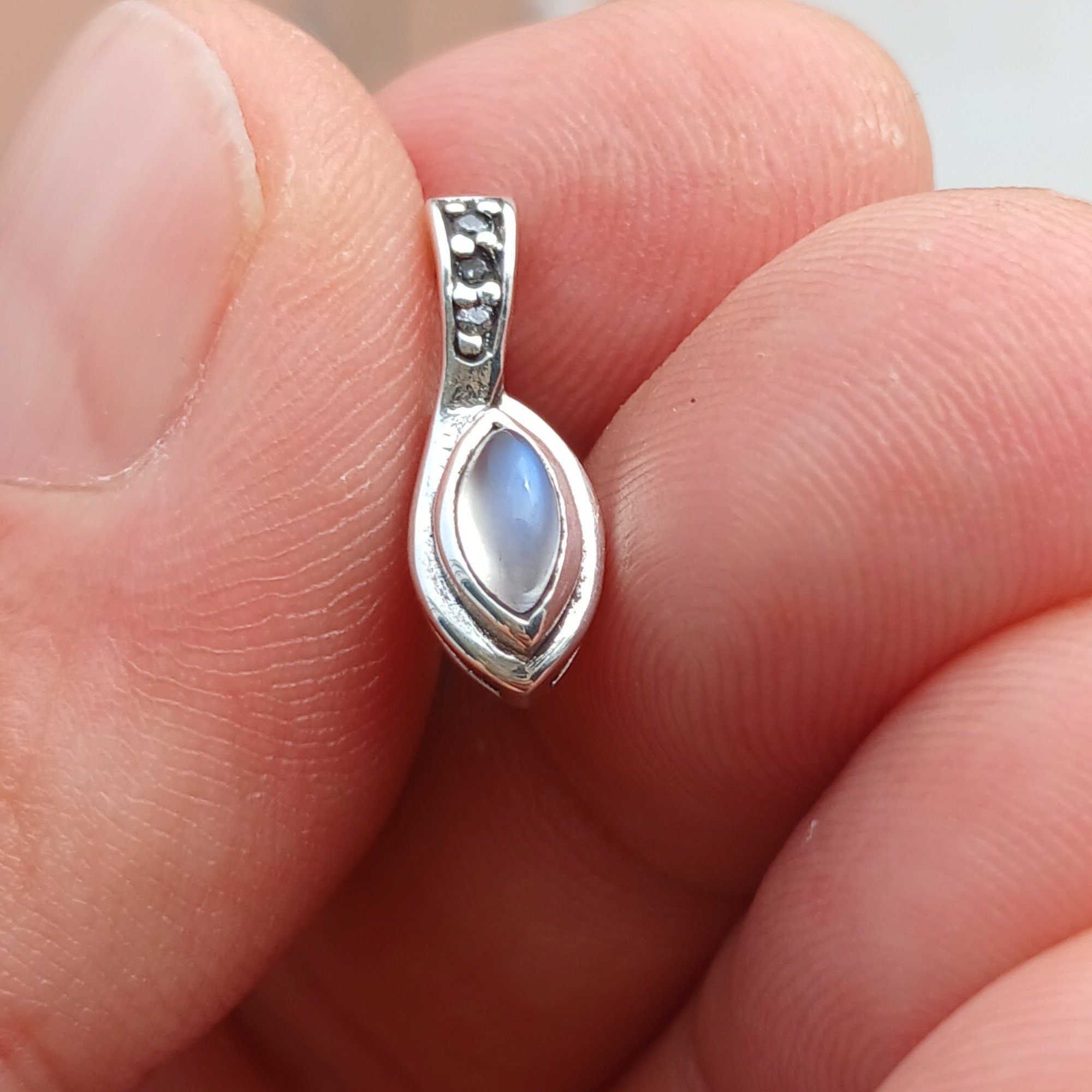 A stunning Moonstone Pendant crafted in sterling silver, featuring a central Ceylon Moonstone surrounded by sparkling Cubic Zirconias.