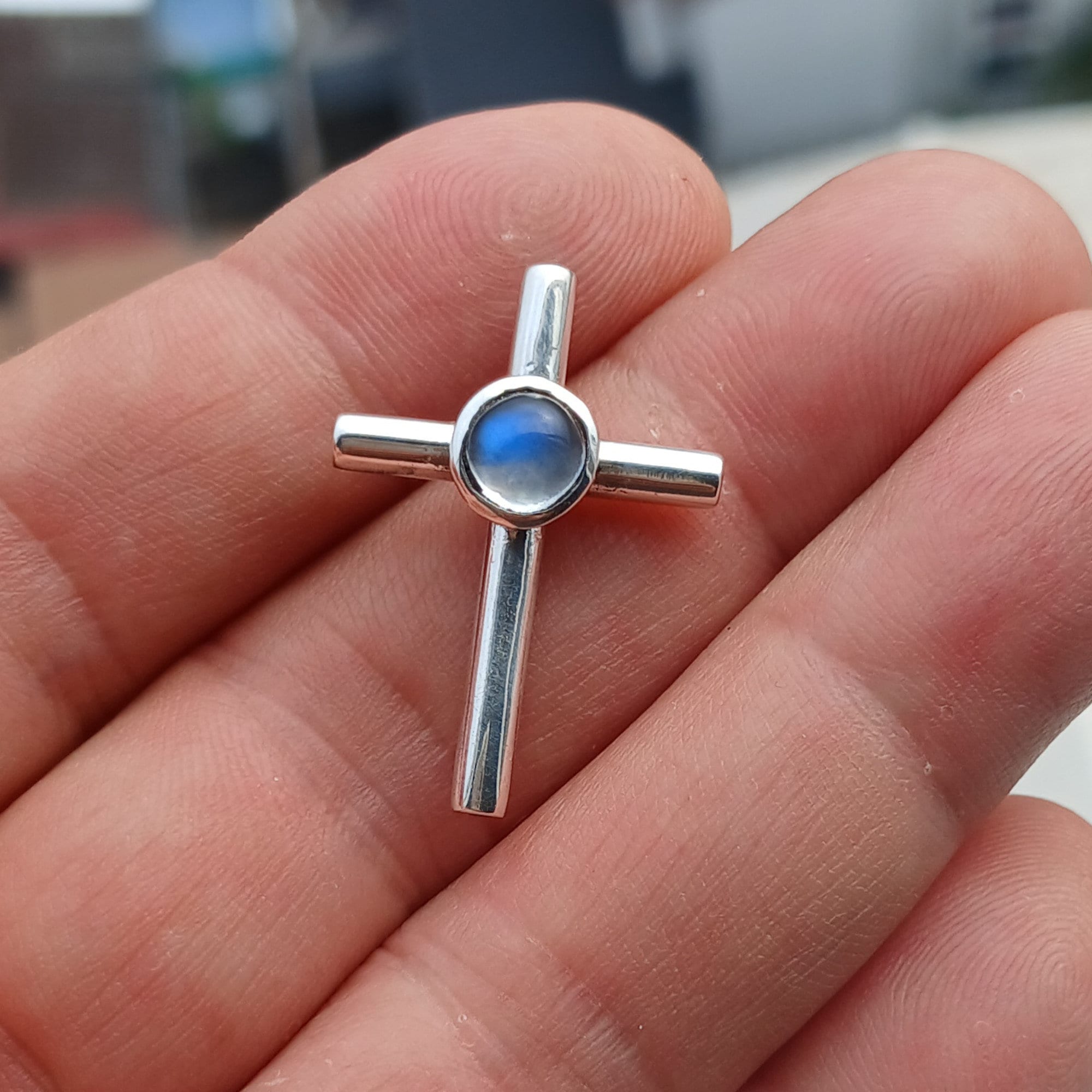 A beautiful Moonstone Pendant in sterling silver featuring a round Ceylon Moonstone at the center and a cross design, showcasing its elegant craftsmanship.
