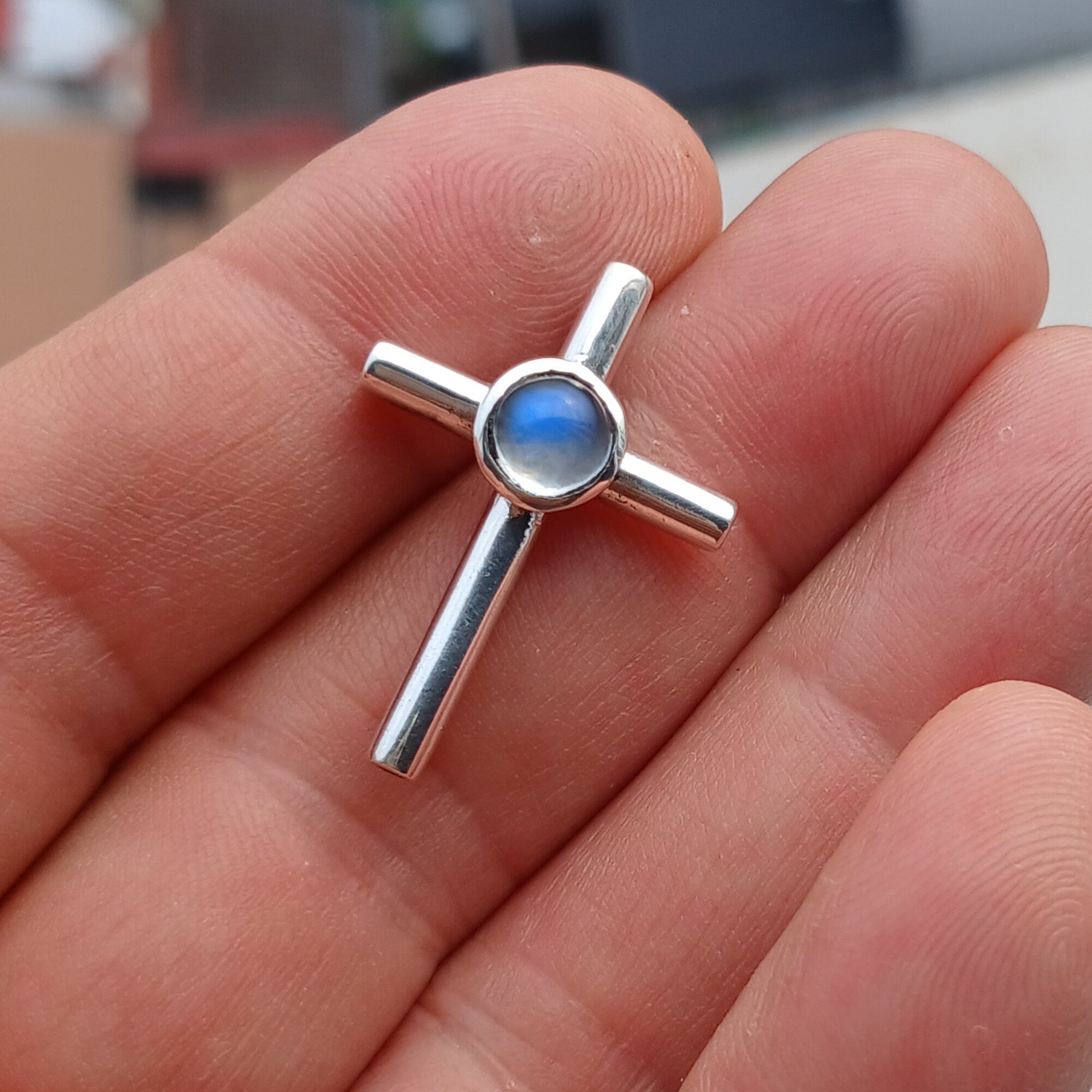 A beautiful Moonstone Pendant in sterling silver featuring a round Ceylon Moonstone at the center and a cross design, showcasing its elegant craftsmanship.