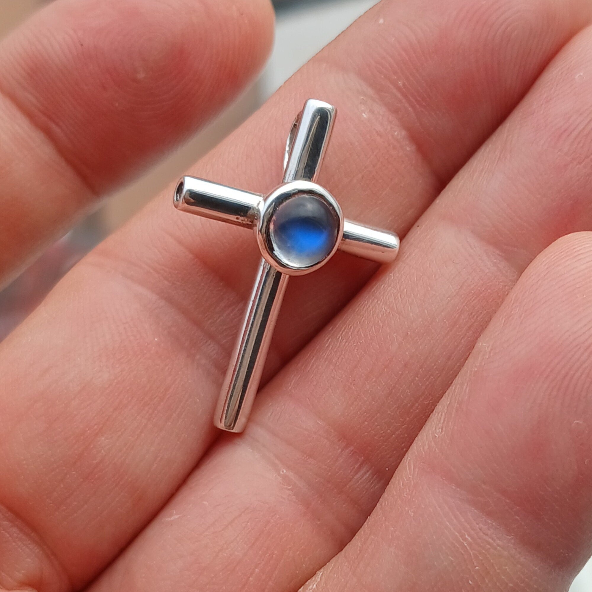 A beautiful Moonstone Pendant in sterling silver featuring a round Ceylon Moonstone at the center and a cross design, showcasing its elegant craftsmanship.