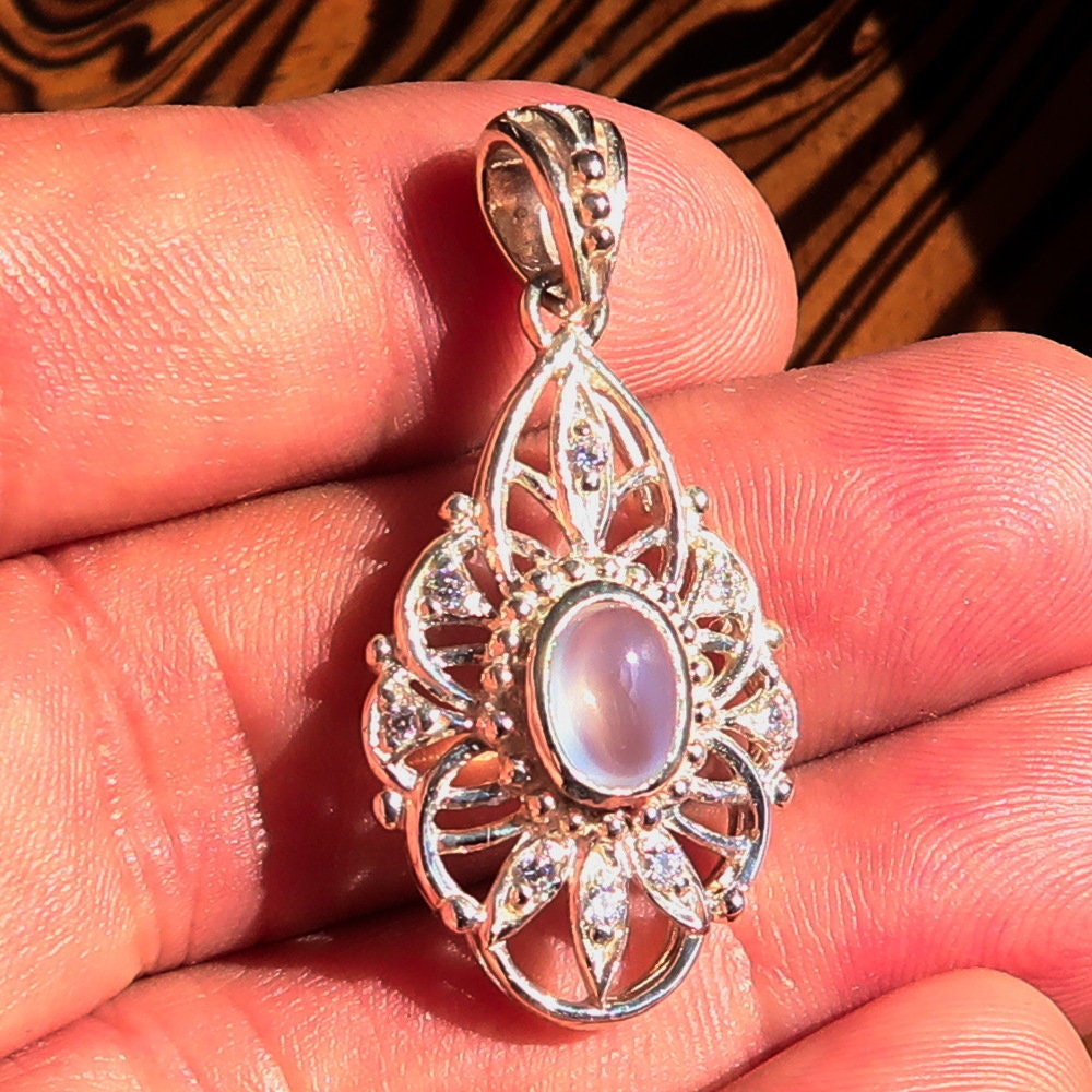 A stunning handmade Moonstone Pendant featuring an oval Ceylon moonstone set in a sterling silver frame, adorned with cubic zirconias.