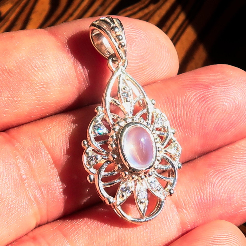 A stunning handmade Moonstone Pendant featuring an oval Ceylon moonstone set in a sterling silver frame, adorned with cubic zirconias.