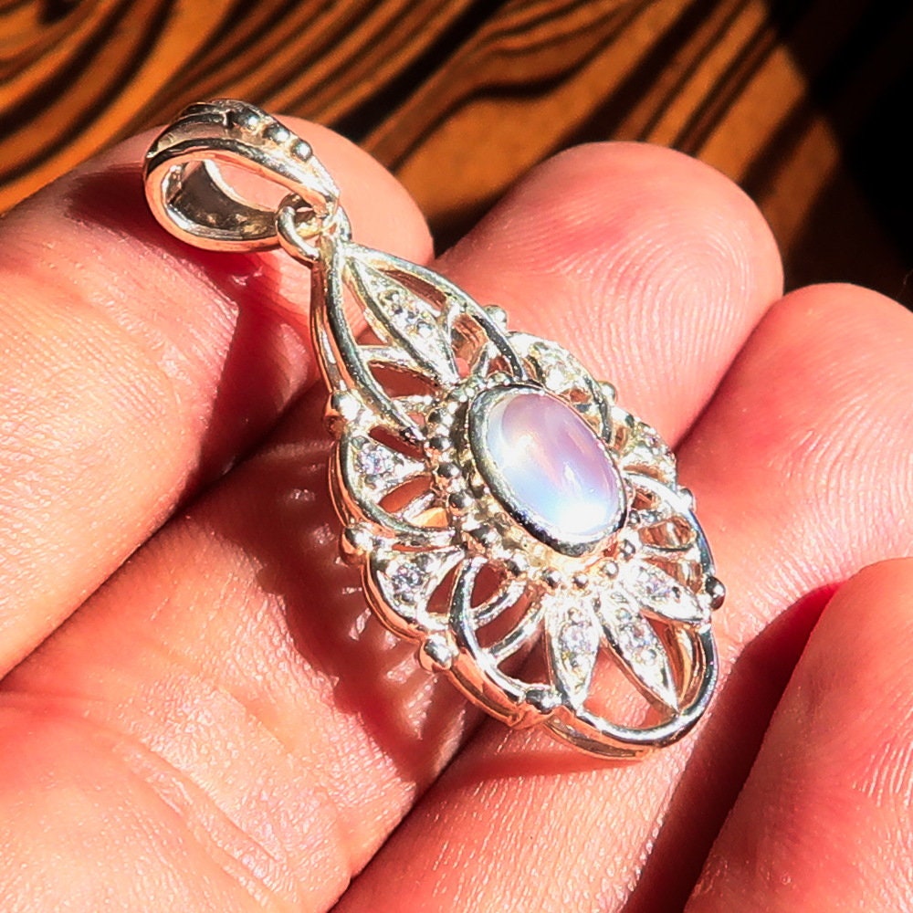 A stunning handmade Moonstone Pendant featuring an oval Ceylon moonstone set in a sterling silver frame, adorned with cubic zirconias.