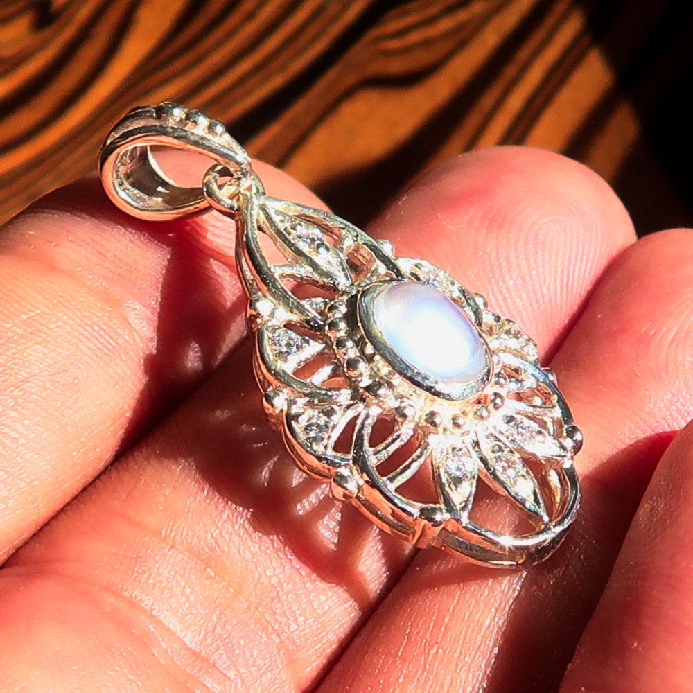 A stunning handmade Moonstone Pendant featuring an oval Ceylon moonstone set in a sterling silver frame, adorned with cubic zirconias.