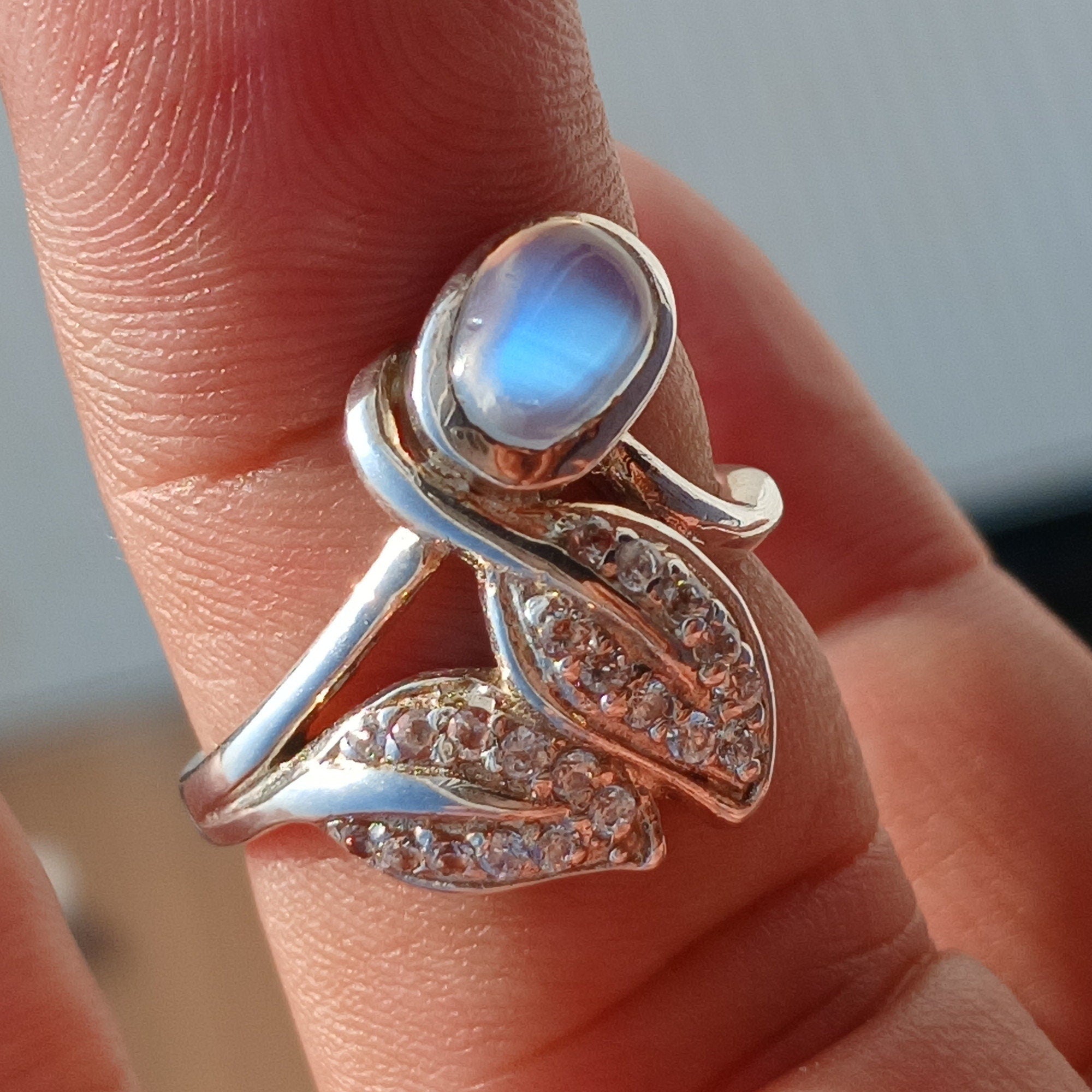 A polished sterling silver ring featuring an oval moonstone, showcasing its unique sheen and elegant design.