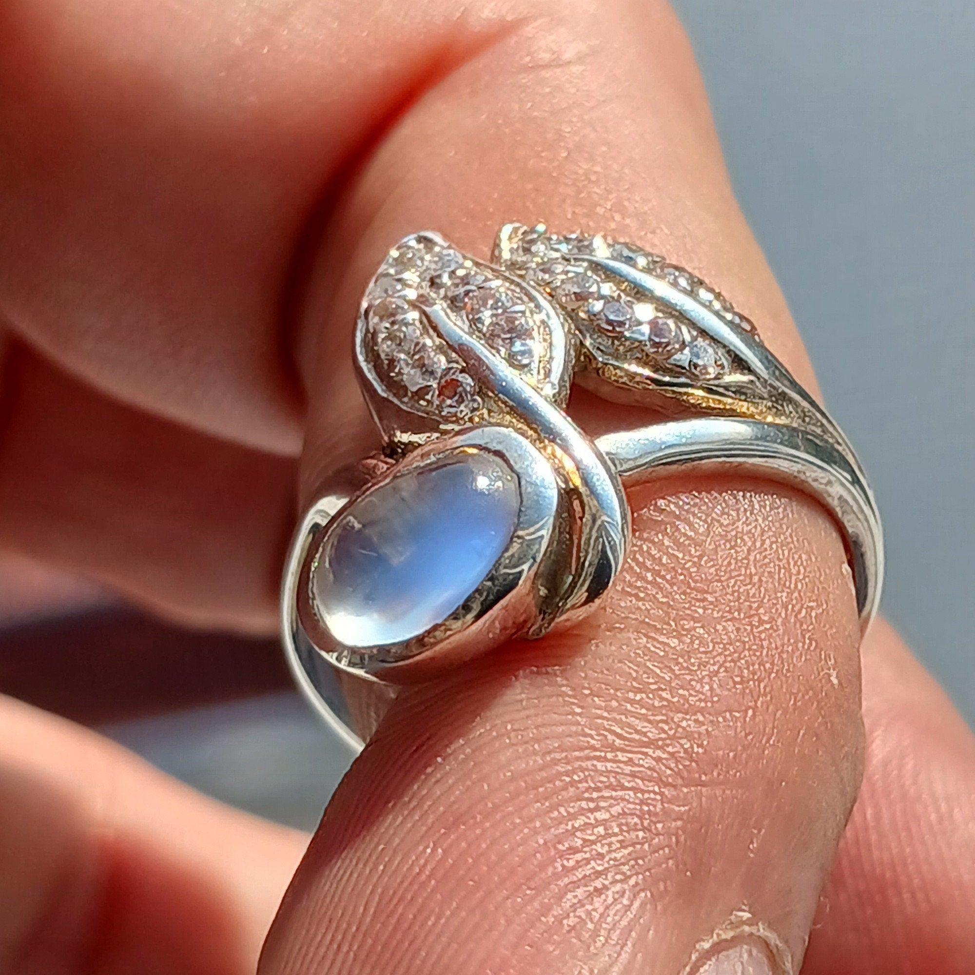 A polished sterling silver ring featuring an oval moonstone, showcasing its unique sheen and elegant design.
