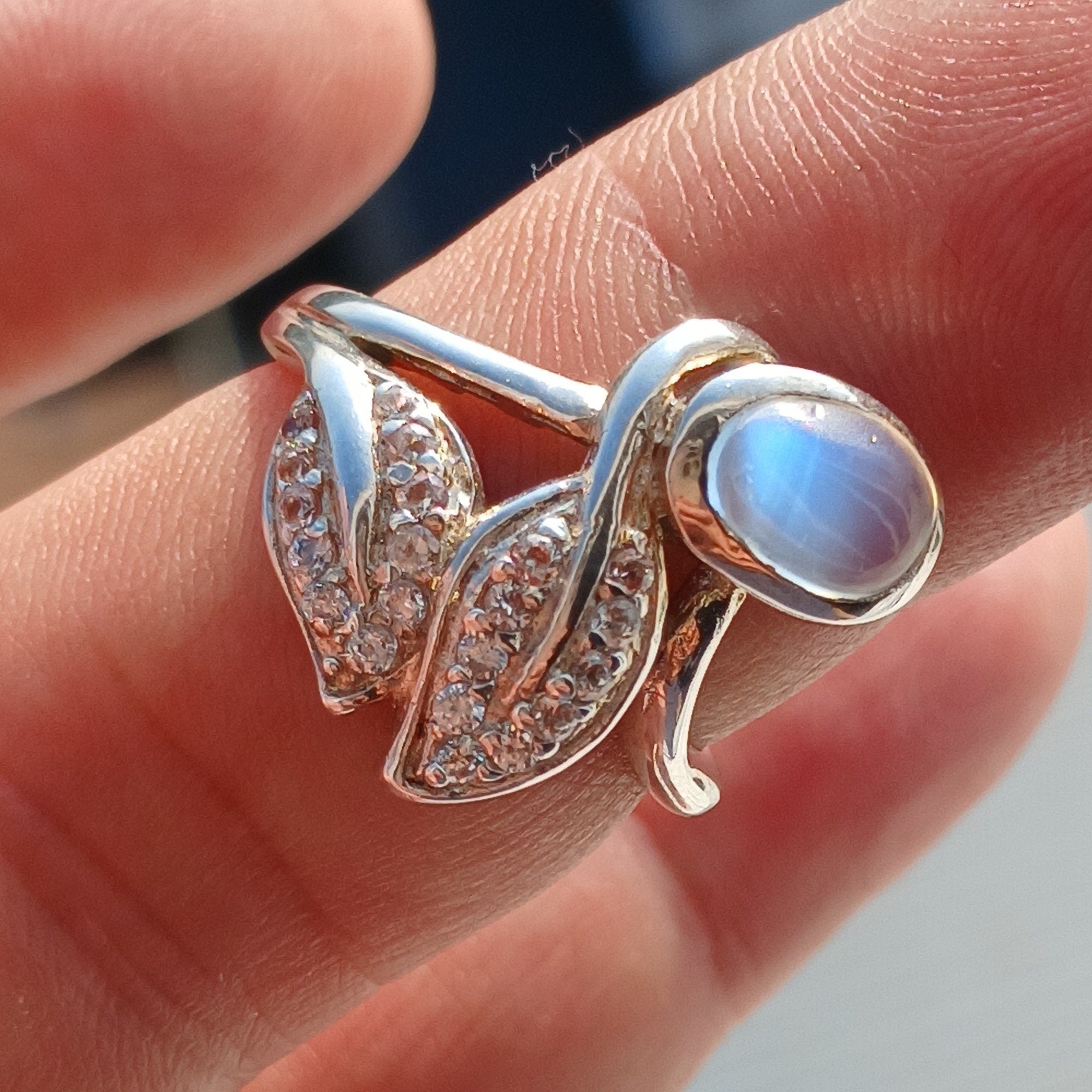 A polished sterling silver ring featuring an oval moonstone, showcasing its unique sheen and elegant design.