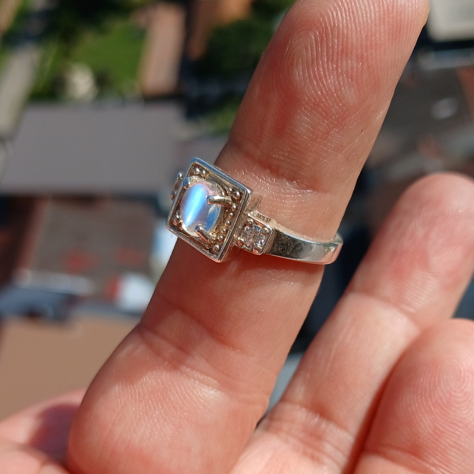 A beautifully polished sterling silver ring featuring an oval moonstone, showcasing a square-shaped design and hallmarked 925.