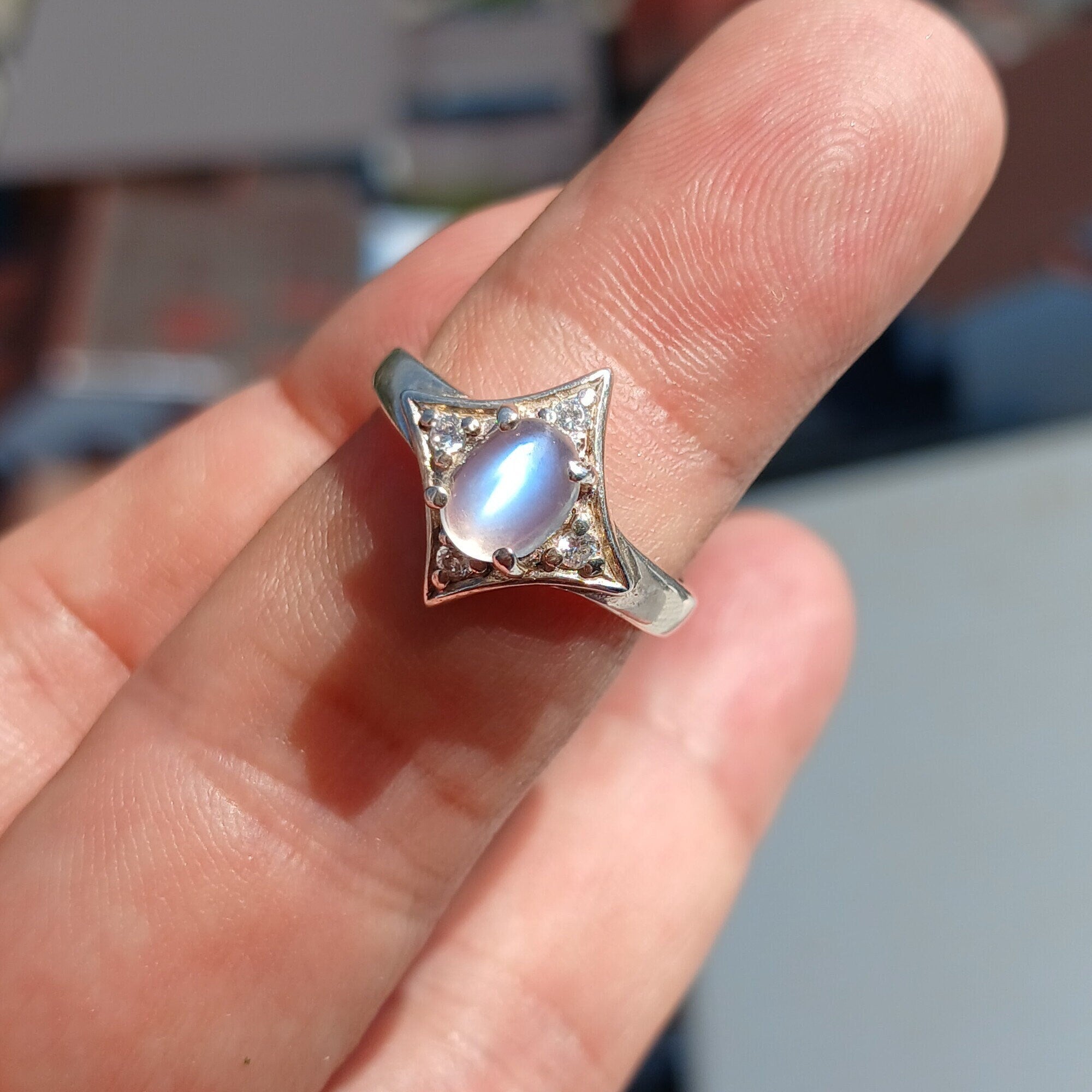 A stunning Moonstone Silver Ring featuring an oval moonstone set in a polished sterling silver band, designed in a star shape.