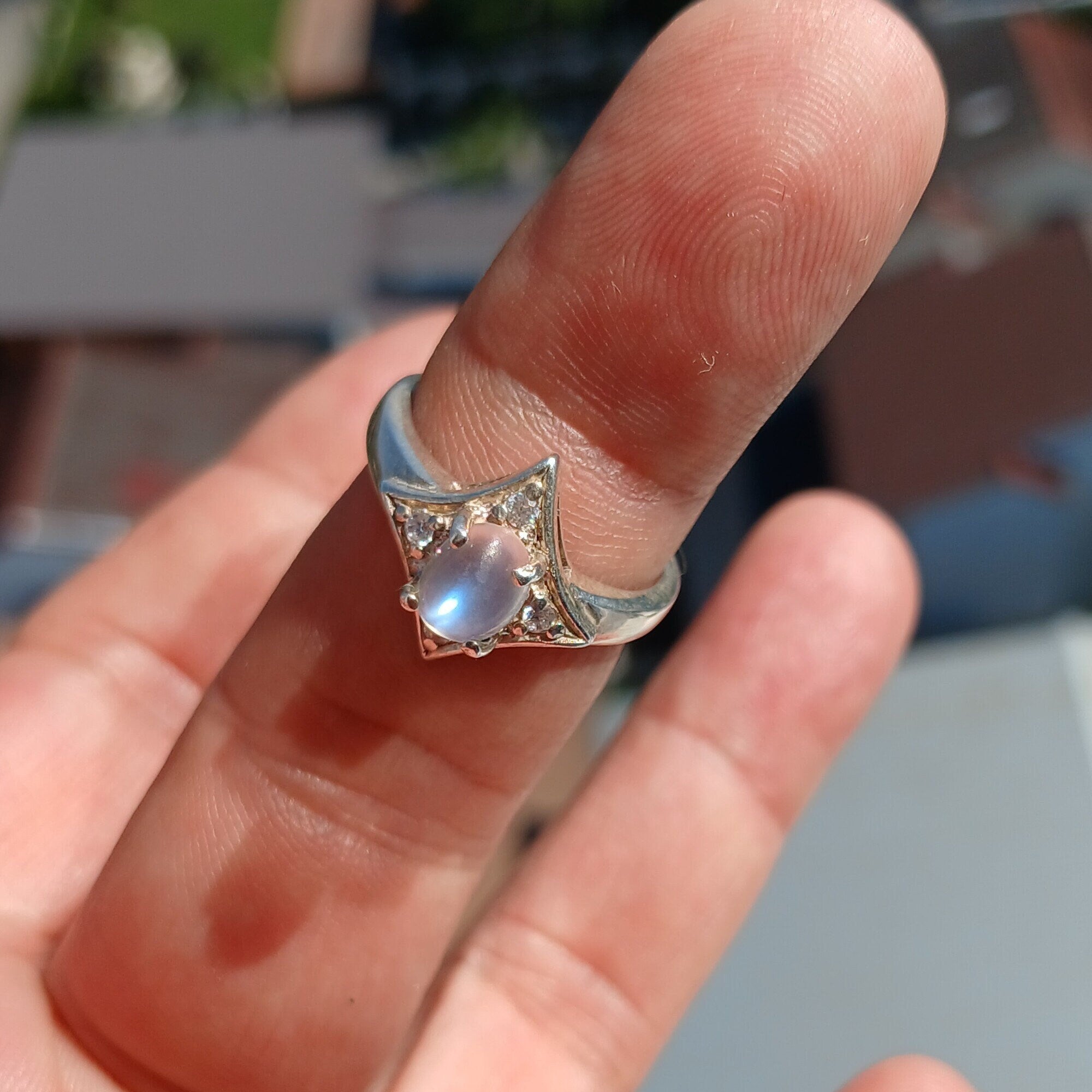 A stunning Moonstone Silver Ring featuring an oval moonstone set in a polished sterling silver band, designed in a star shape.
