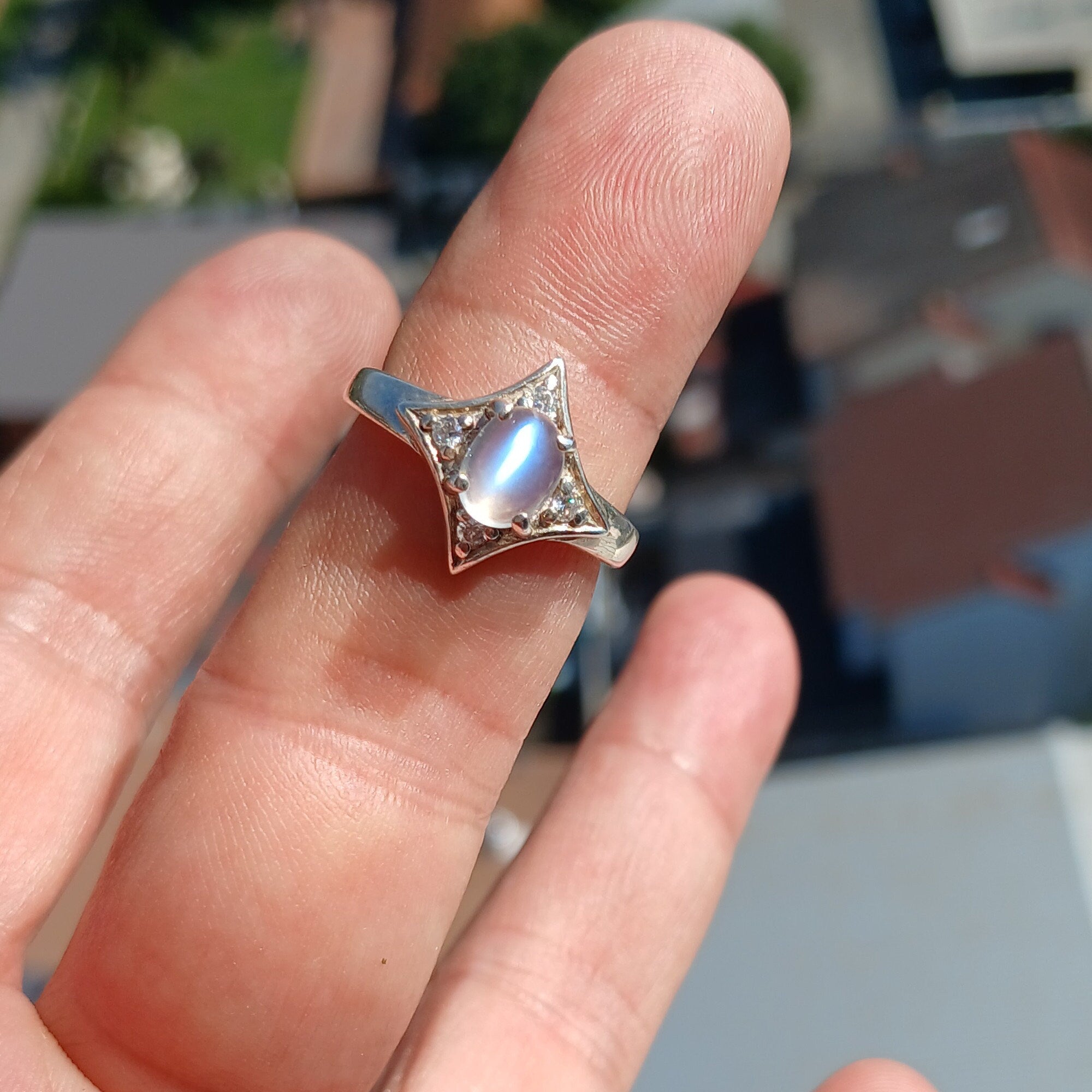 A stunning Moonstone Silver Ring featuring an oval moonstone set in a polished sterling silver band, designed in a star shape.