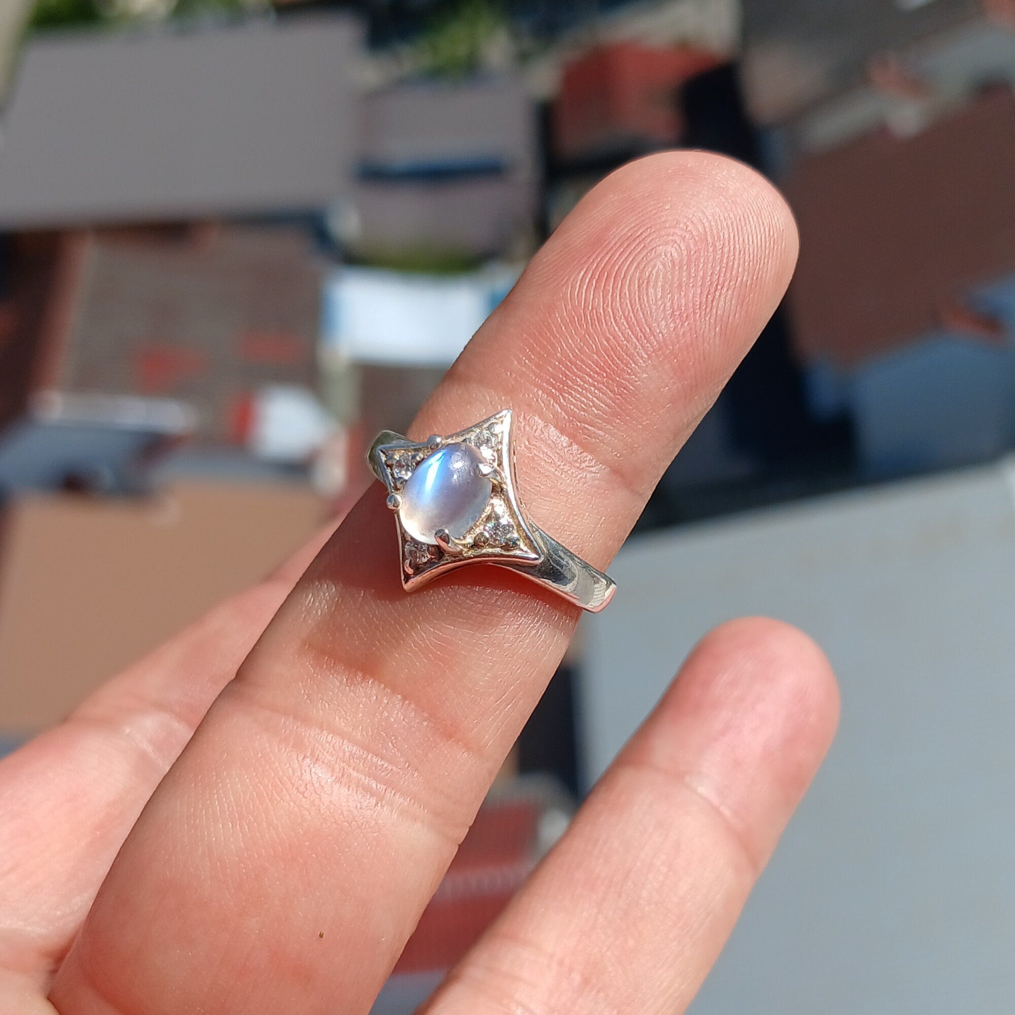 A stunning Moonstone Silver Ring featuring an oval moonstone set in a polished sterling silver band, designed in a star shape.