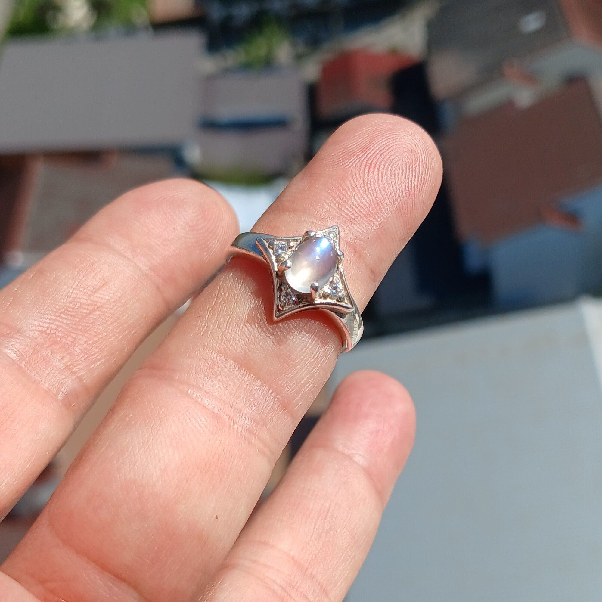 A stunning Moonstone Silver Ring featuring an oval moonstone set in a polished sterling silver band, designed in a star shape.
